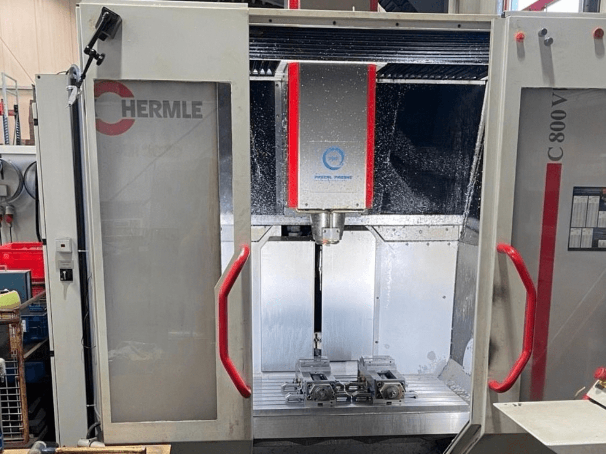 HERMLE C800V verticaal bewerkingscentrum, vooraanzicht van het bewerkingsgebied met werkstukken en vloeibare koelvloeistof.