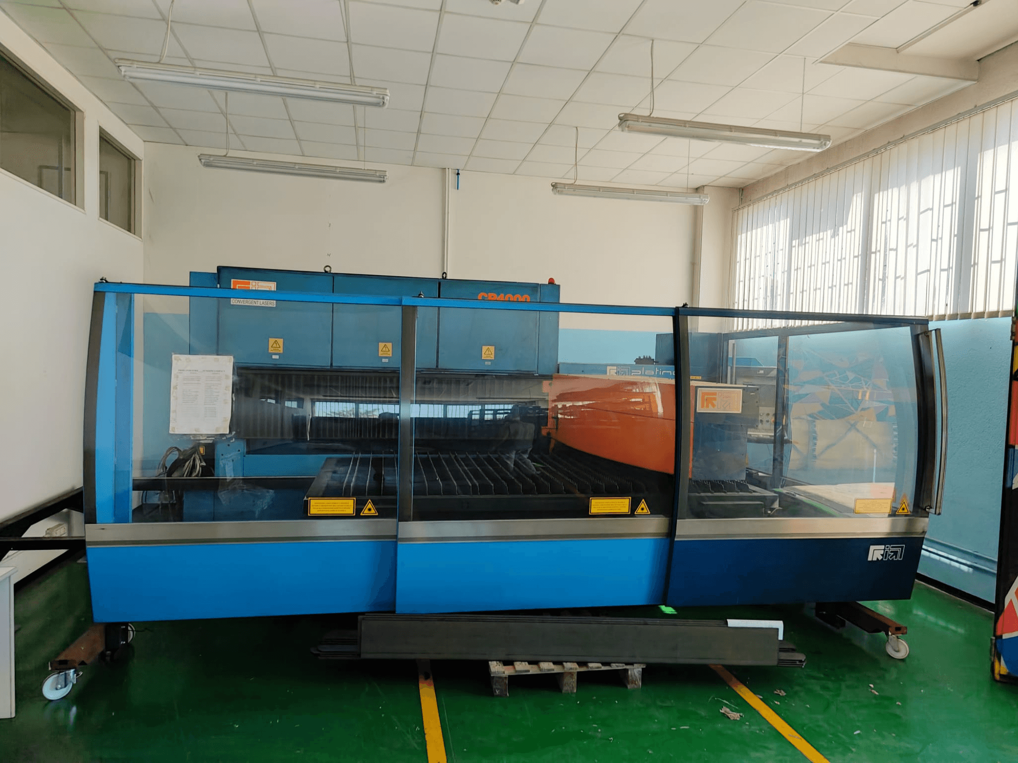 Vooraanzicht van een CONVERGENT LASERS CP4000 CO₂-lasersnijmachine met een blauw-oranje ontwerp, in een goed verlichte werkplaats.