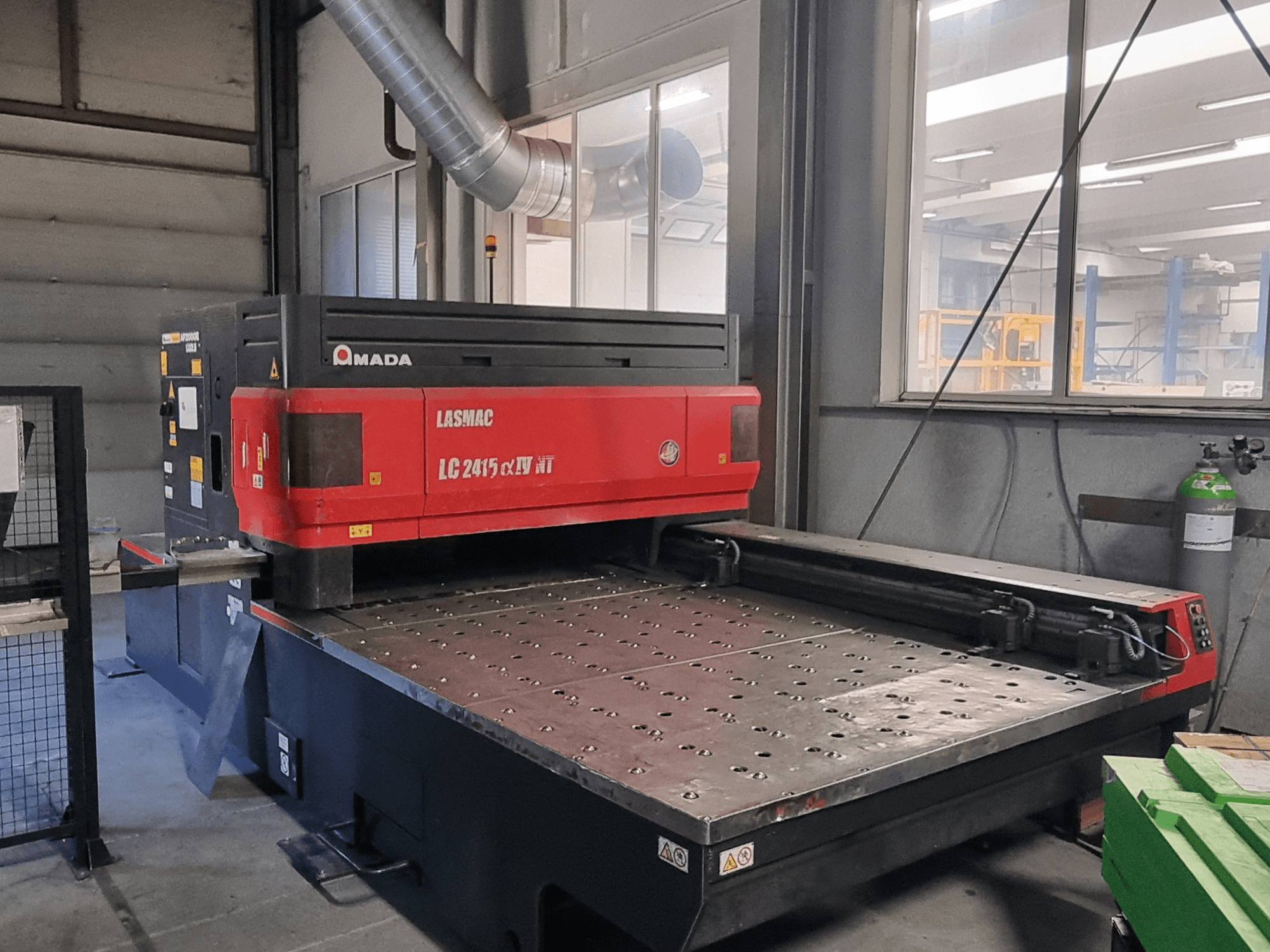 Amada LASMAC LC 2415 αⅡ NT lasersnijmachine in rood en zwart, vooraanzicht, met aangedreven snijbed en precisiebesturing.