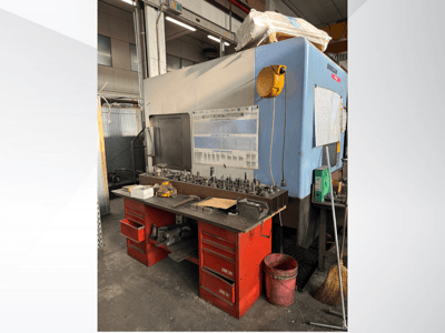 Doosan bewerkingscentrum met een rode werkbank en opslag, waar gereedschap en apparatuur worden getoond, gezien vanaf de voorkant.