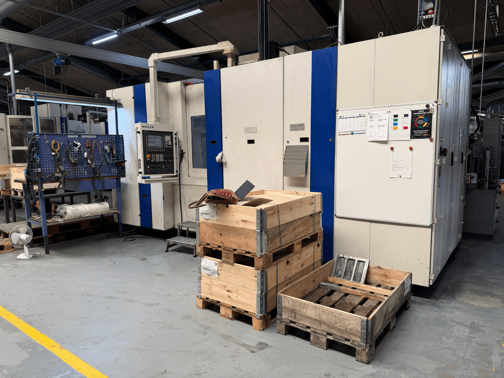 HORIZONTALE BEWERKINGSCENTRUM HELLER MCH 250 in werkplaats, zijaanzicht met houten pallets en gereedschapsrek zichtbaar.