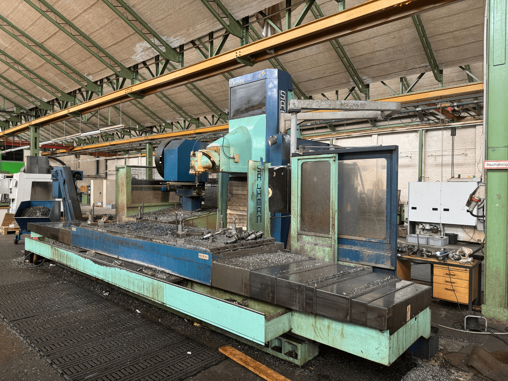 Salvador freesmachine in fabrieksopstelling, vooraanzicht, met een blauw en groen kleurenschema, met metaalschilfers op het bed.