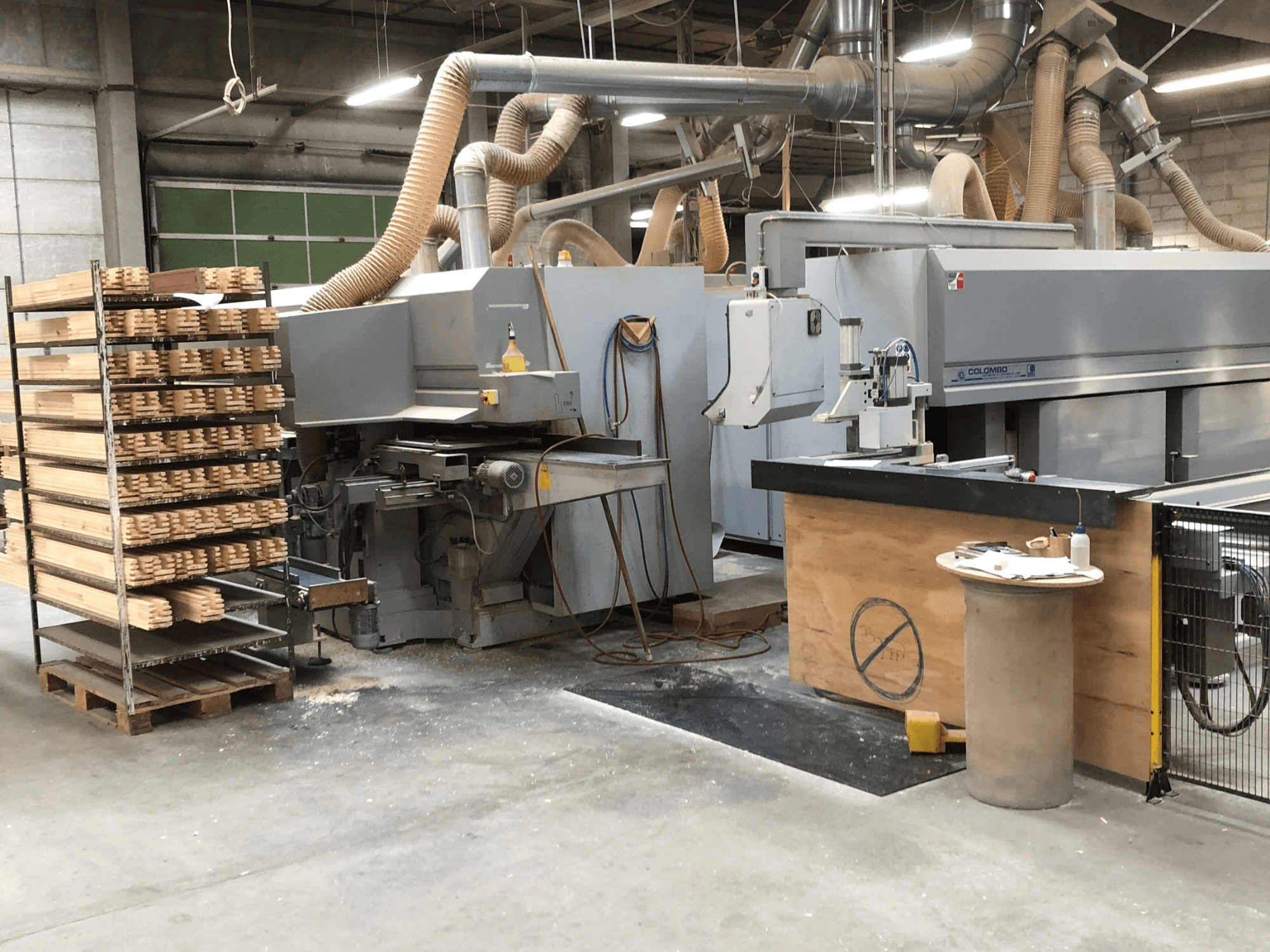 Colombo AM 60 freesmachine, zijaanzicht, met stapels houtstukken ernaast en een zichtbaar stofafzuigsysteem.