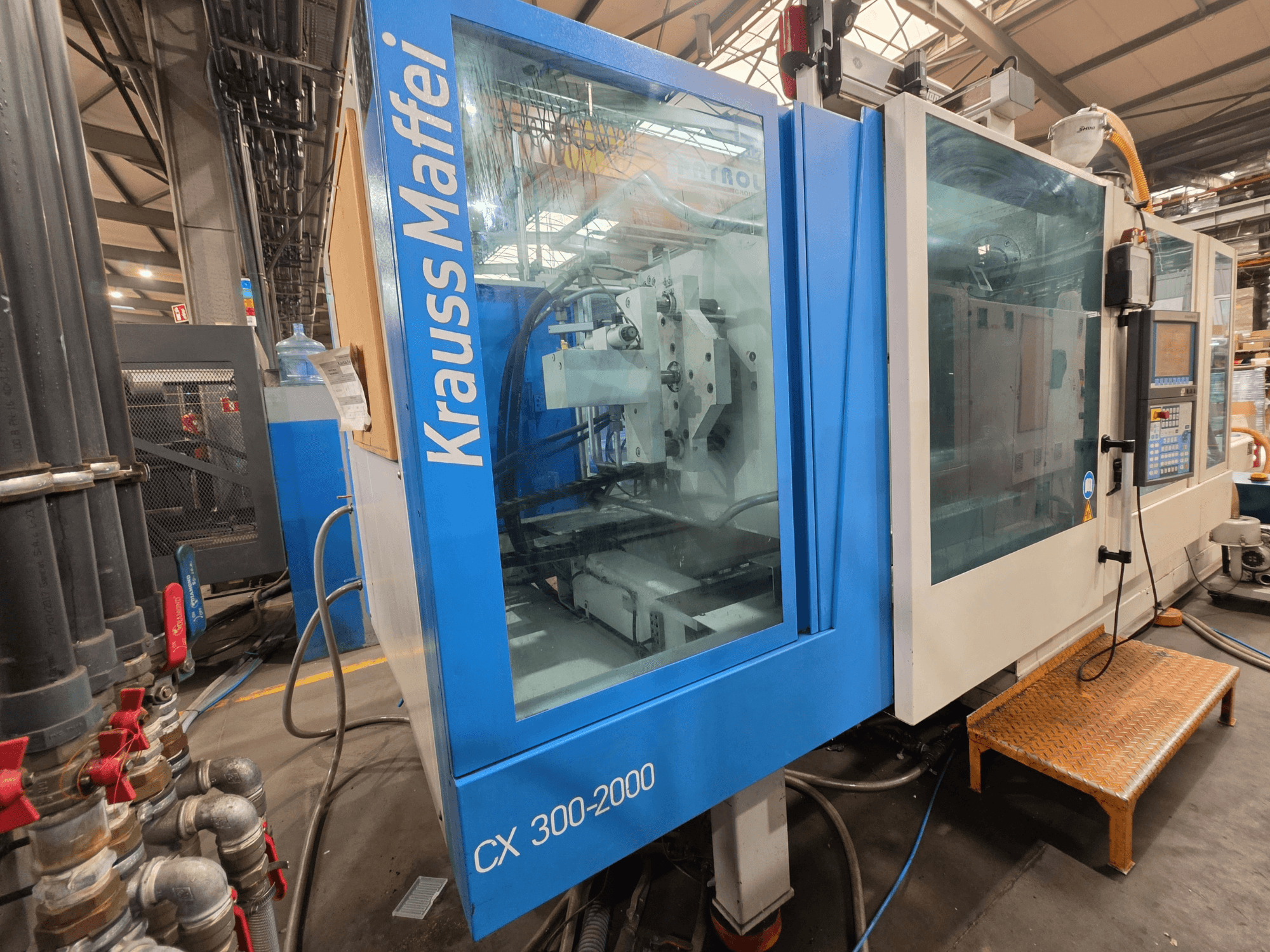 Krauss Maffei CX 300-2000 hydraulische spuitgietmachine, vooraanzicht, met het bedieningspaneel en de hydraulische leidingen.