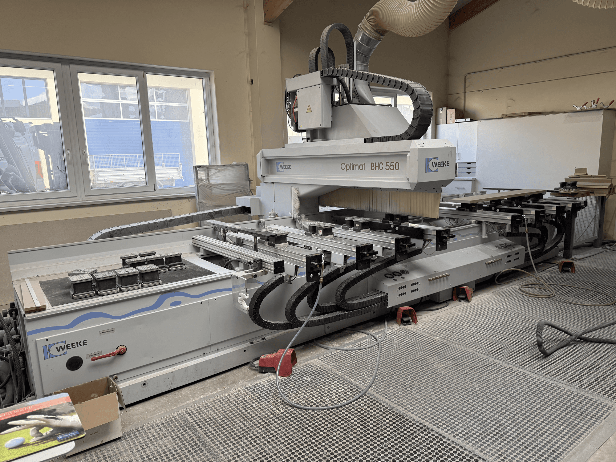 CNC houtbewerkingscentrum Weeke Optimat BHC 550, vooraanzicht met gereedschapskop en werktafel, stofafzuigsysteem zichtbaar.