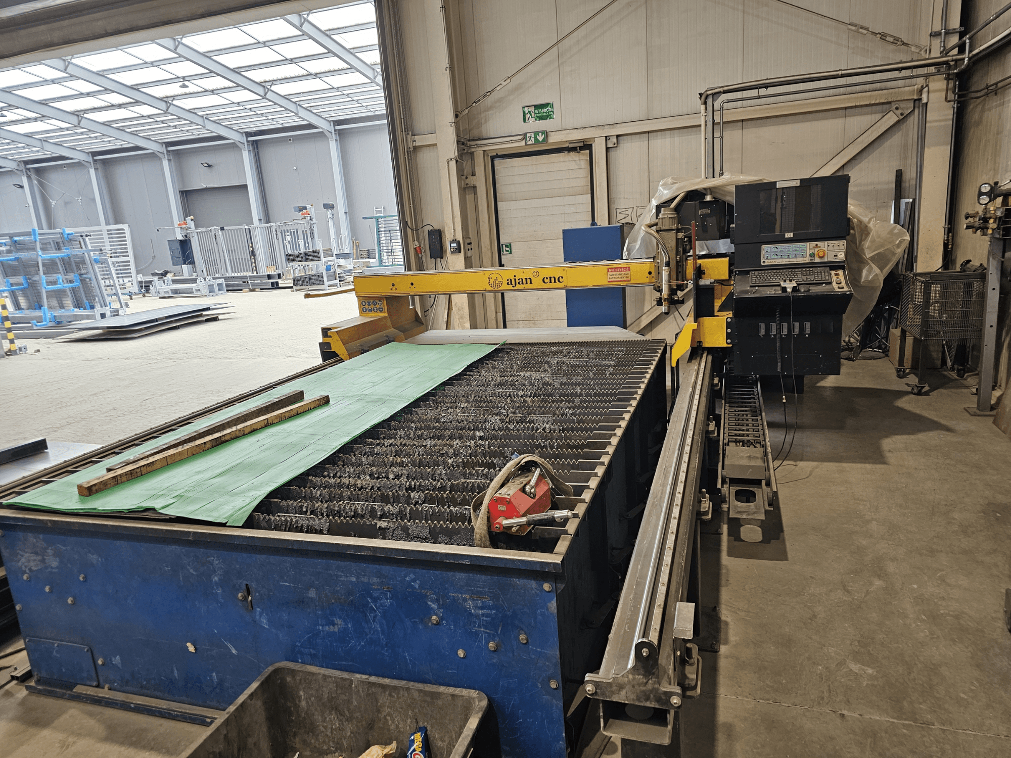 AJAN PP16011 automatische plasmasnijmachine in zijaanzicht, met snijtafel en bedieningspaneel, opgesteld in een werkplaatsomgeving.