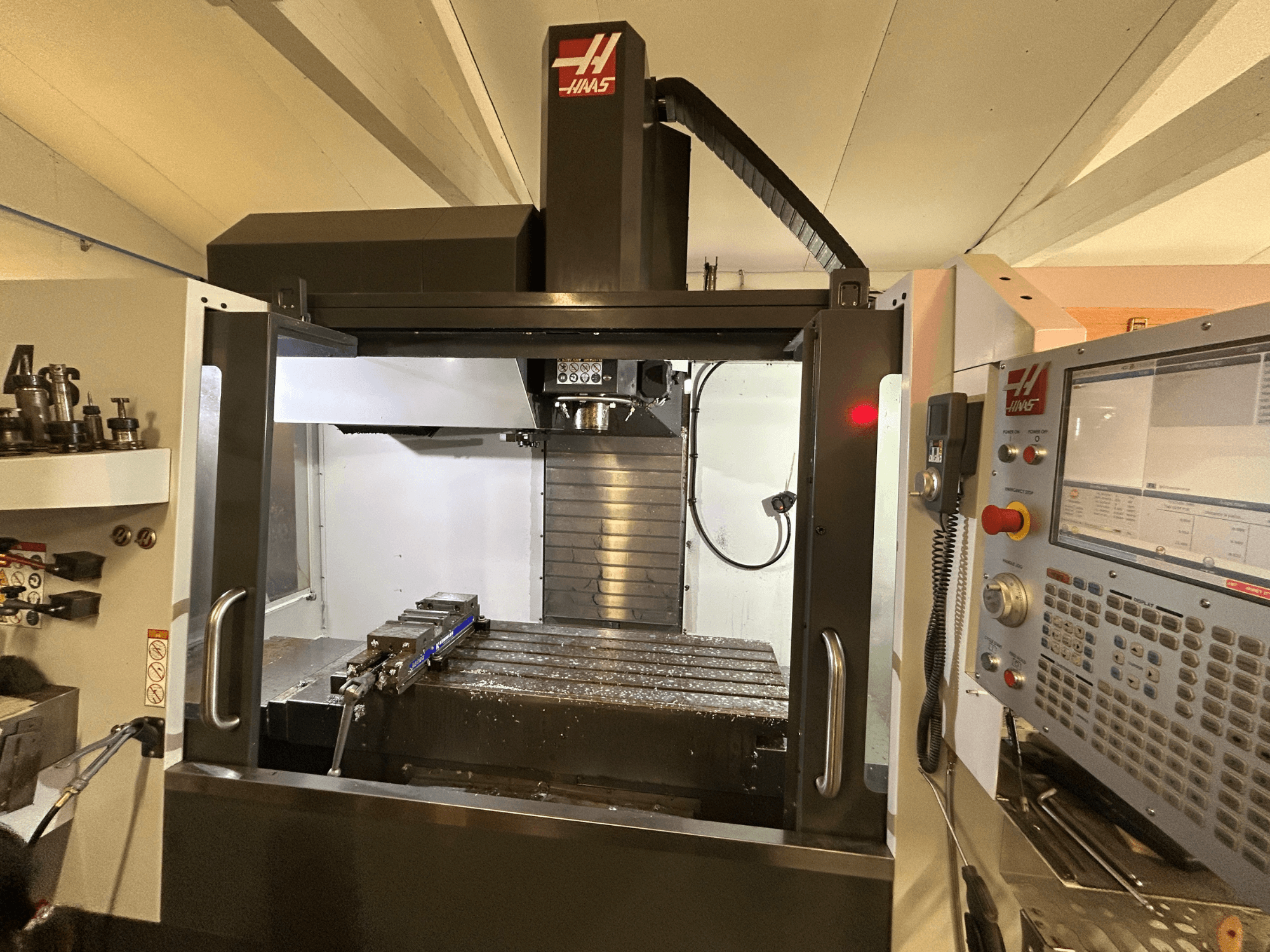 HAAS VF-4SS verticaal bewerkingscentrum, vooraanzicht, met het bedieningspaneel, de gereedschapshouder en het werkgebied met metaalspanen.