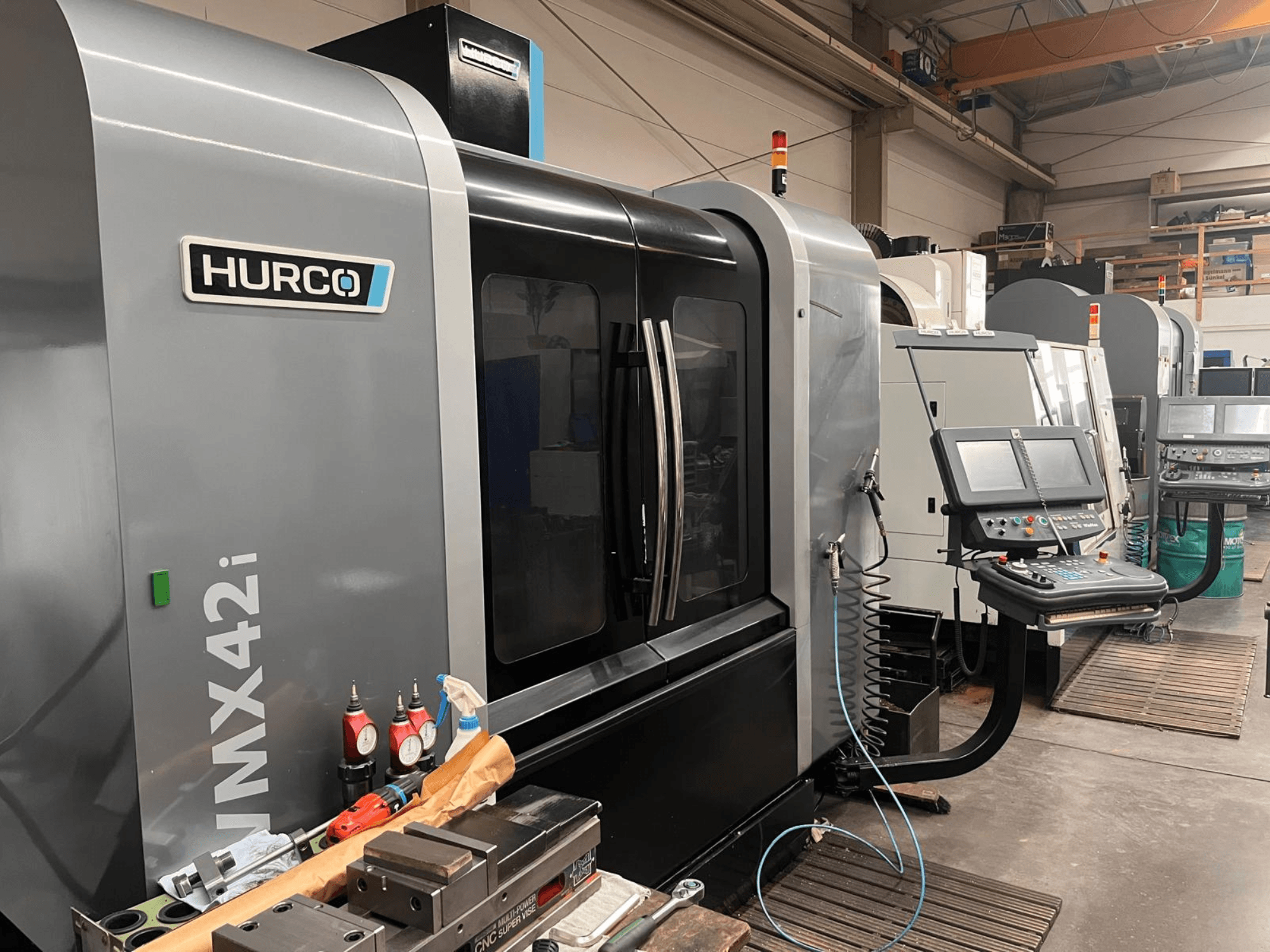 Hurco VMX42i CNC machine in een werkplaats, vooraanzicht, met bedieningspaneel en diverse gereedschappen op de werkbank.