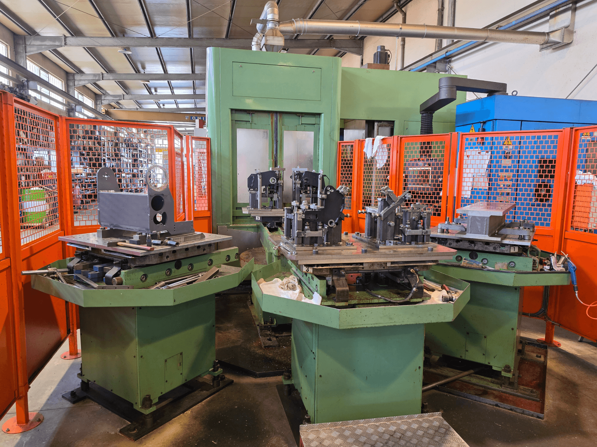 Vooraanzicht van het Mandelli R.S. M7U horizontaal bewerkingscentrum met drie werkstations, metalen onderdelen en veiligheidsafschermingen.