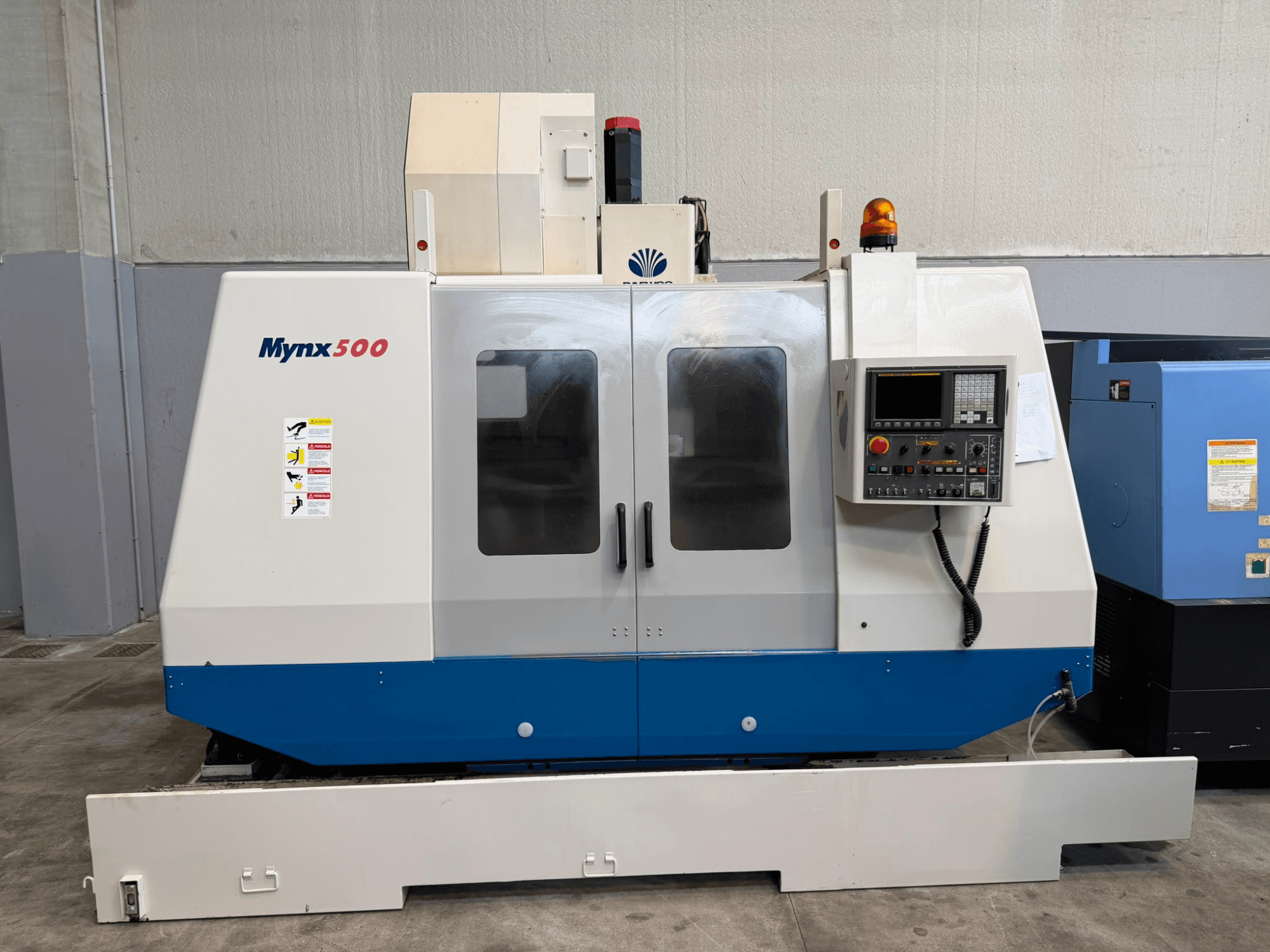 DAEWOO MYNX 500 verticaal bewerkingscentrum, gezien van voren, met een bedieningspaneel, veiligheidslampjes en doorzichtige toegangsdeuren.