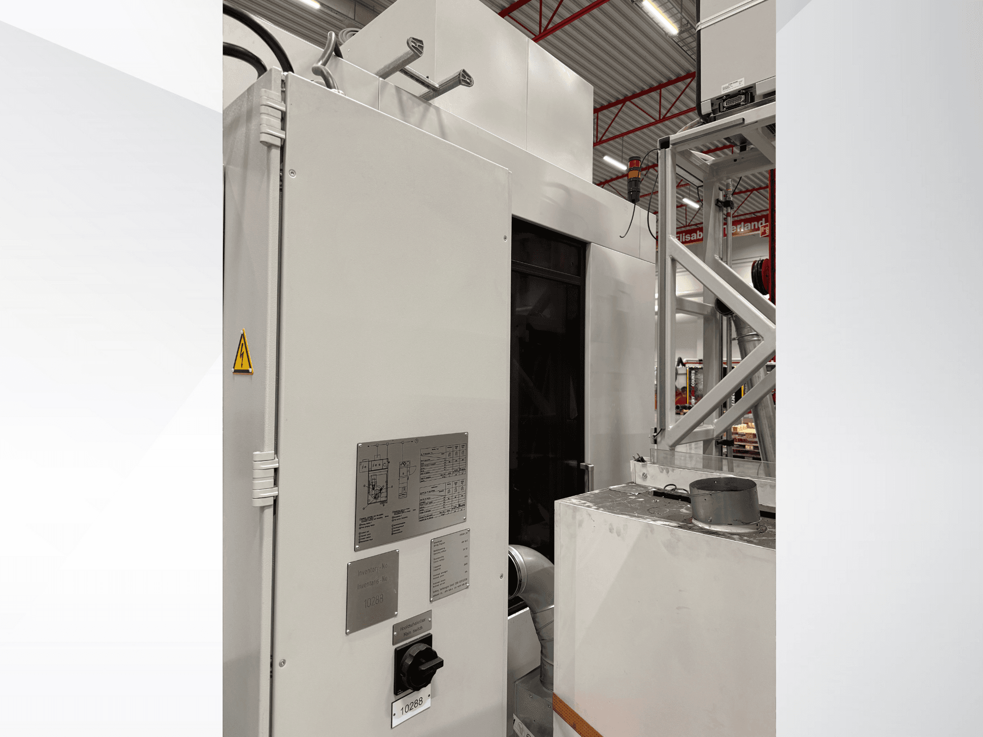 Zijaanzicht van een witte industriële machine met bedieningspaneel en waarschuwingslabel, onderdeel van een geautomatiseerd systeem.