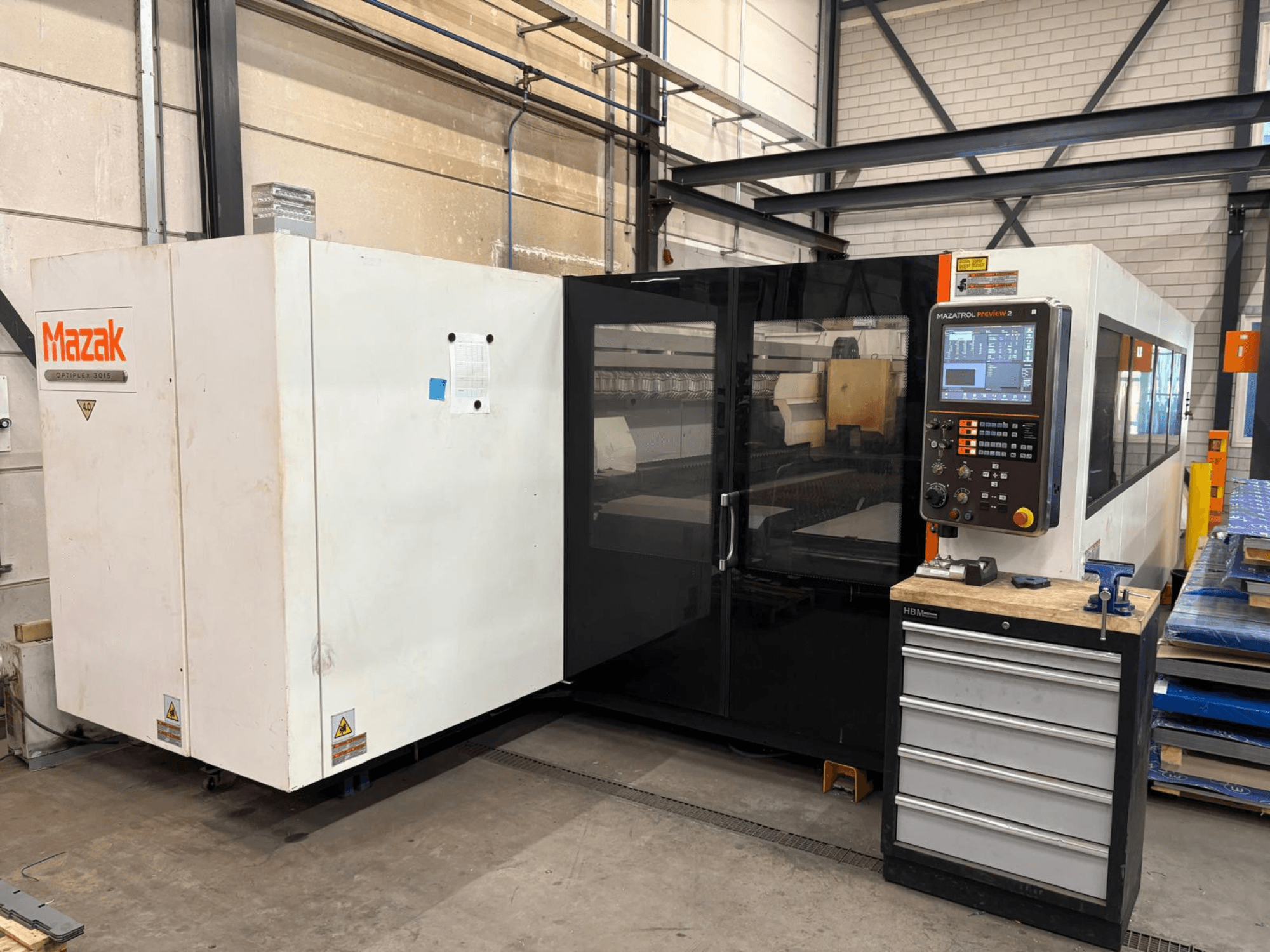 Mazak Optiplex 3015 CO₂-lasersnijmachine, vooraanzicht, met weergave van het bedieningspaneel en de industriële opstelling.