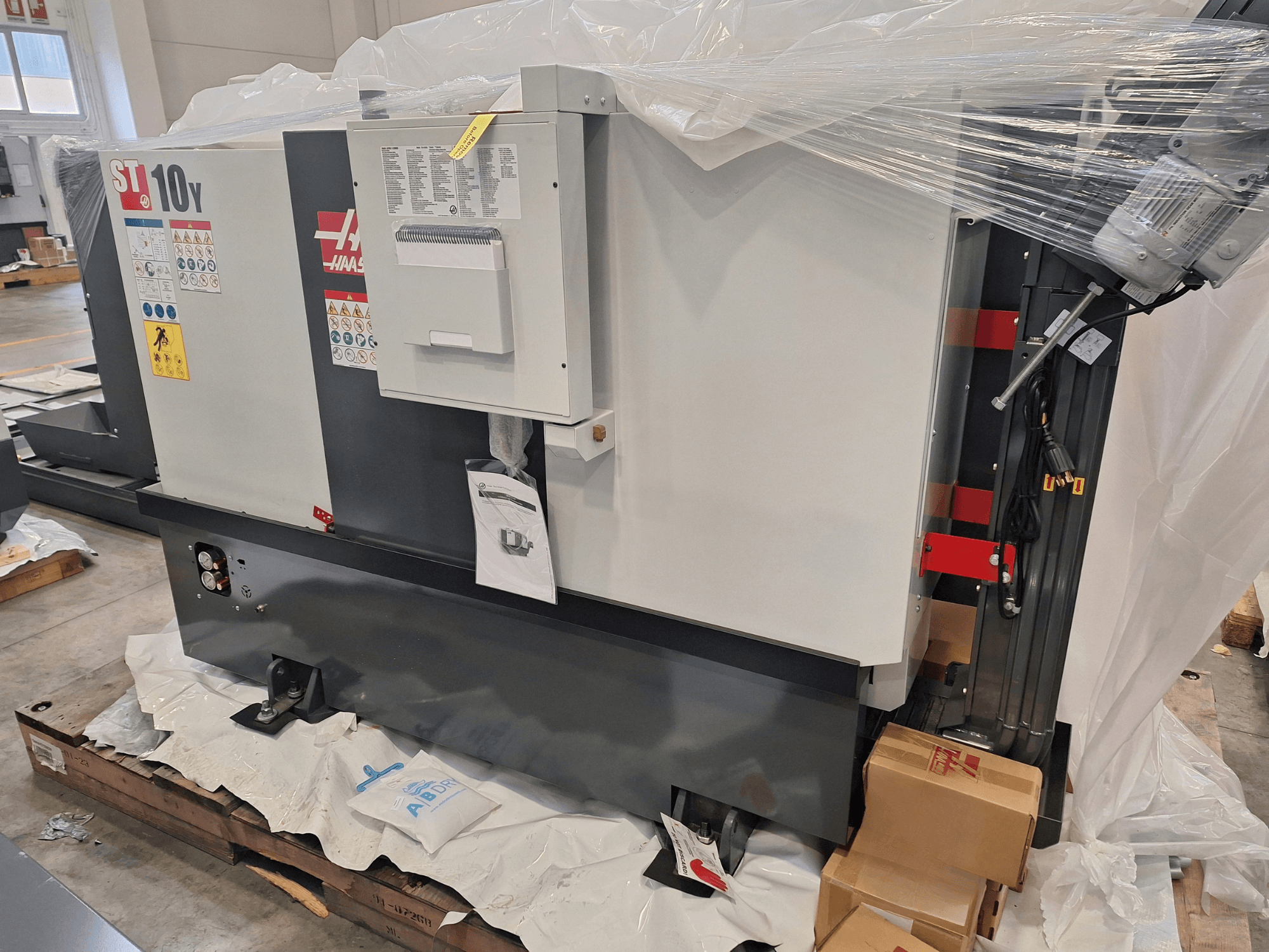 HAAS ST-10Y EU horizontale draaibank, zijaanzicht, in plastic verpakt, met zichtbaar bedieningspaneel en waarschuwingsstickers.