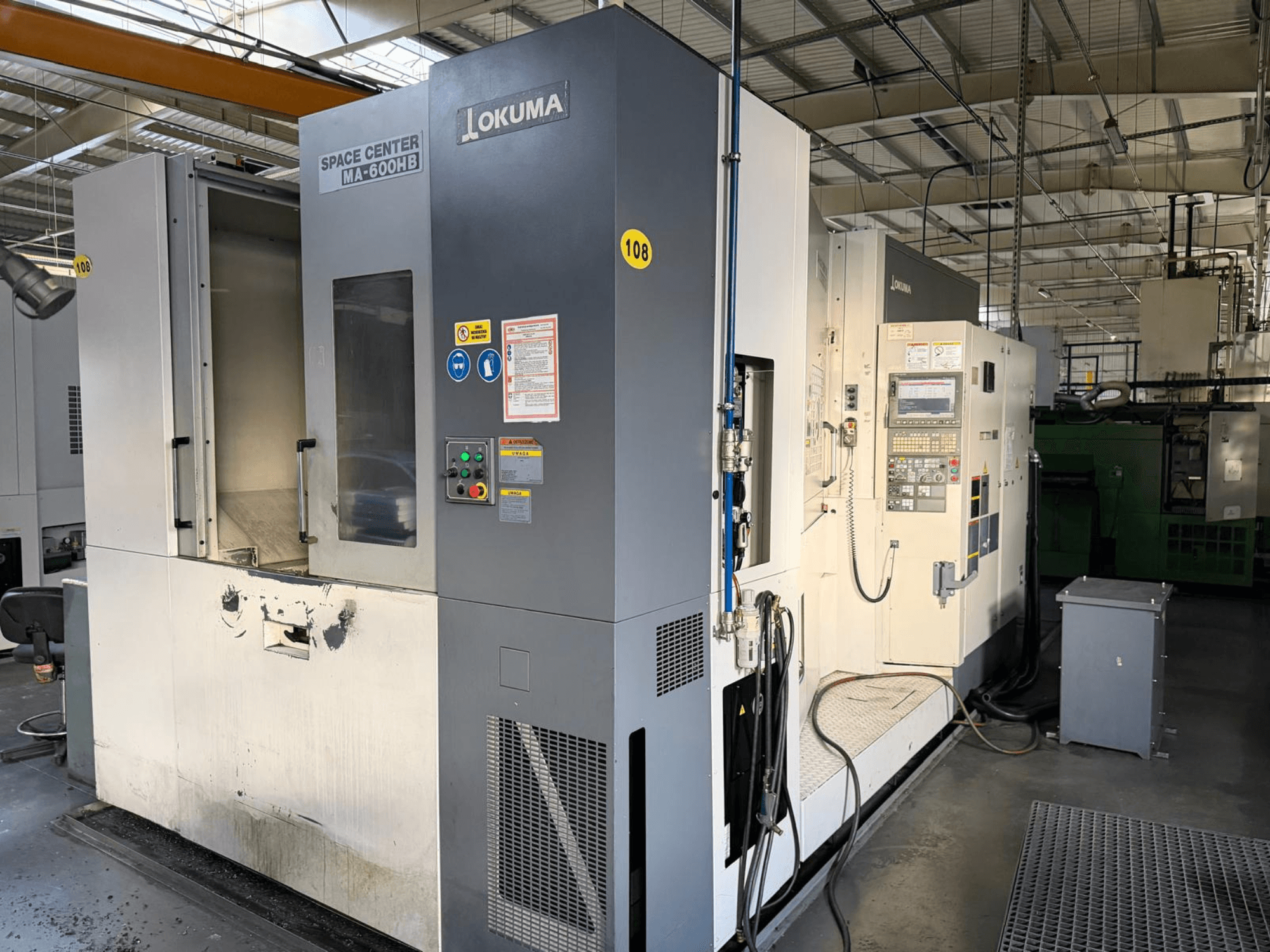 Okuma MA-600 HB horizontaal bewerkingscentrum, vooraanzicht, met het bedieningspaneel en het snijgedeelte met zichtbare slijtagesporen.