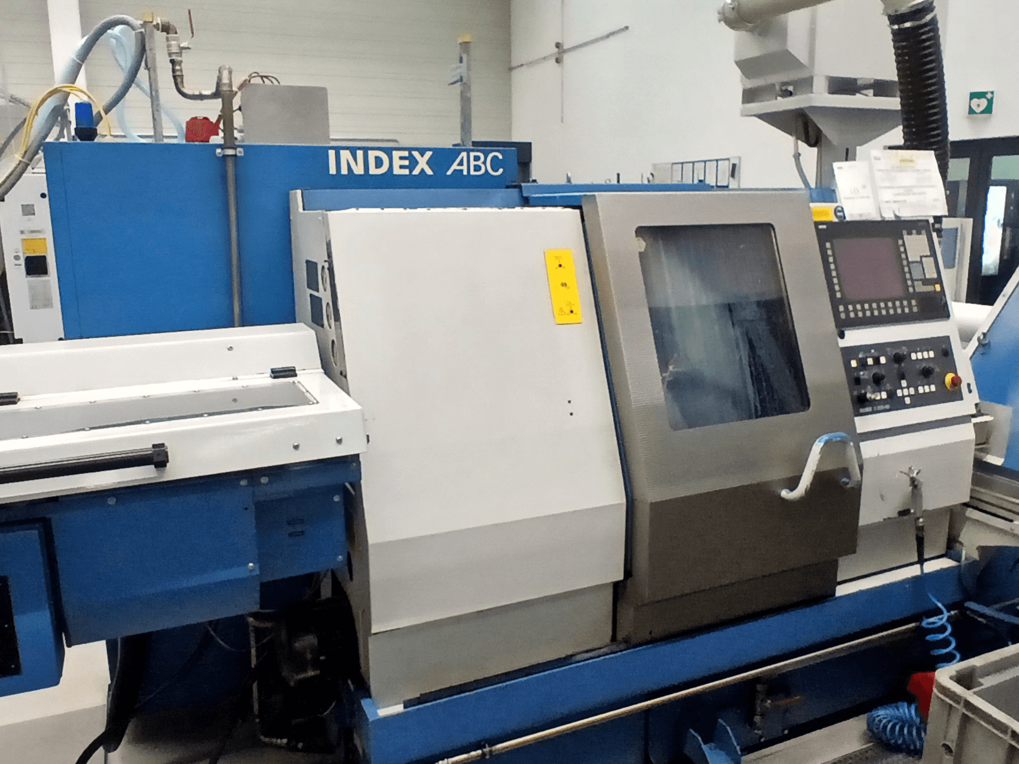 Horizontale draaimachine Index ABC in blauw en zilver, vooraanzicht met bedieningspaneel en werkgebied.