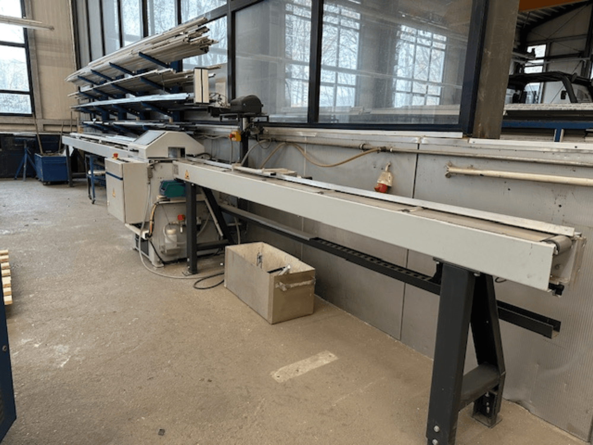 SCHÜCO PGS metaalcirkelzaag in een werkplaats, zijaanzicht met een verstelbaar zaagbed en een plank met metalen profielen erboven.