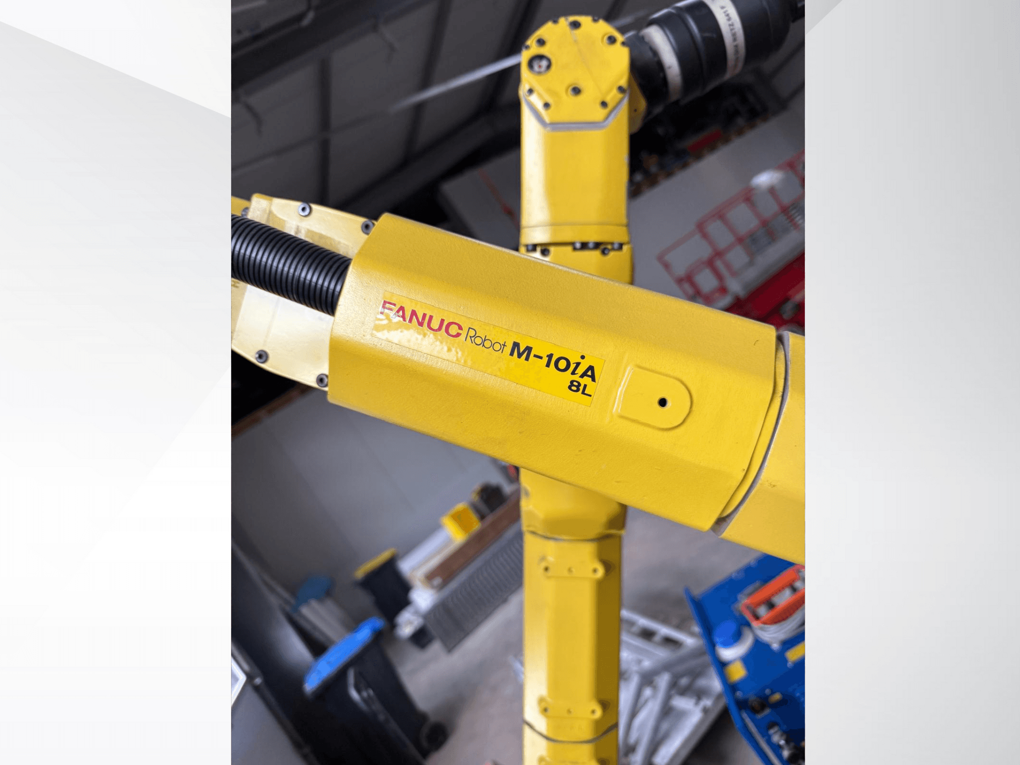 FANUC Robot M-10iA 8L in geel, van opzij gezien, toont het armgewricht en de mechanische componenten in een industriële omgeving.
