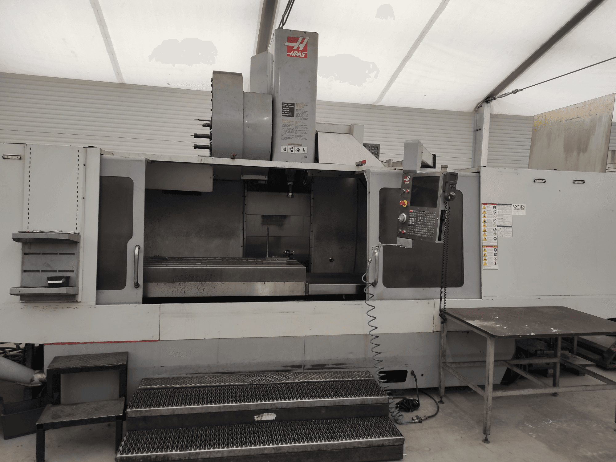 HAAS VF-10/50HE verticaal bewerkingscentrum, vooraanzicht met bedieningspaneel, machinebed en toegankelijke opstap voor bediening.