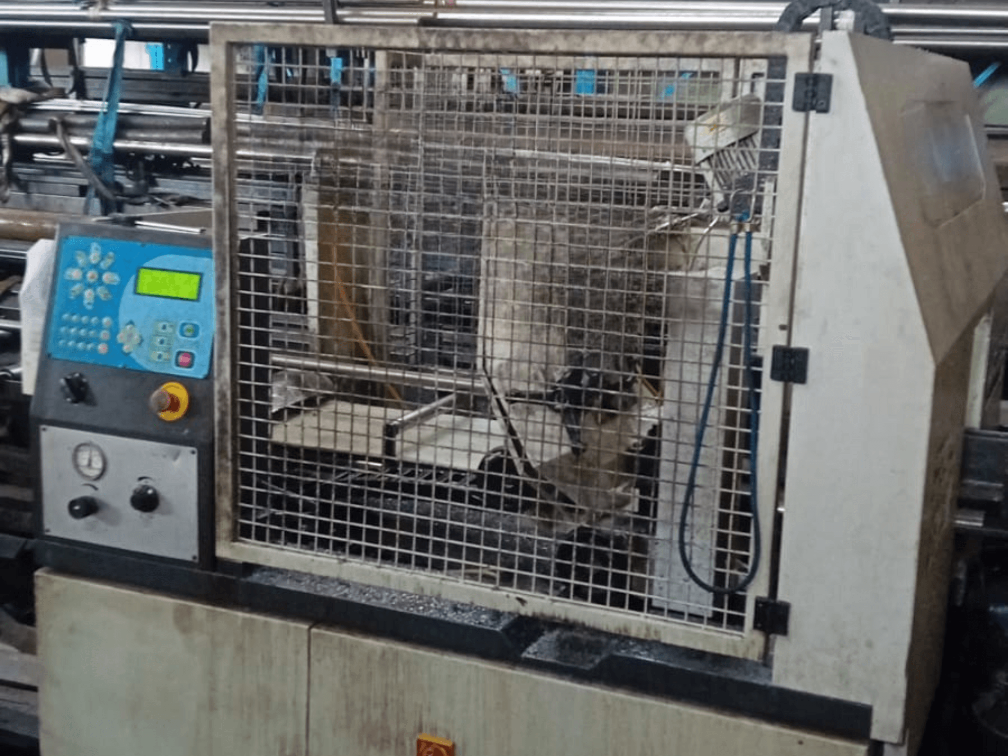 Metalen lintzaag Macc 381 AV, vooraanzicht, met bedieningspaneel, veiligheidskooi en metaalresten op de basis.