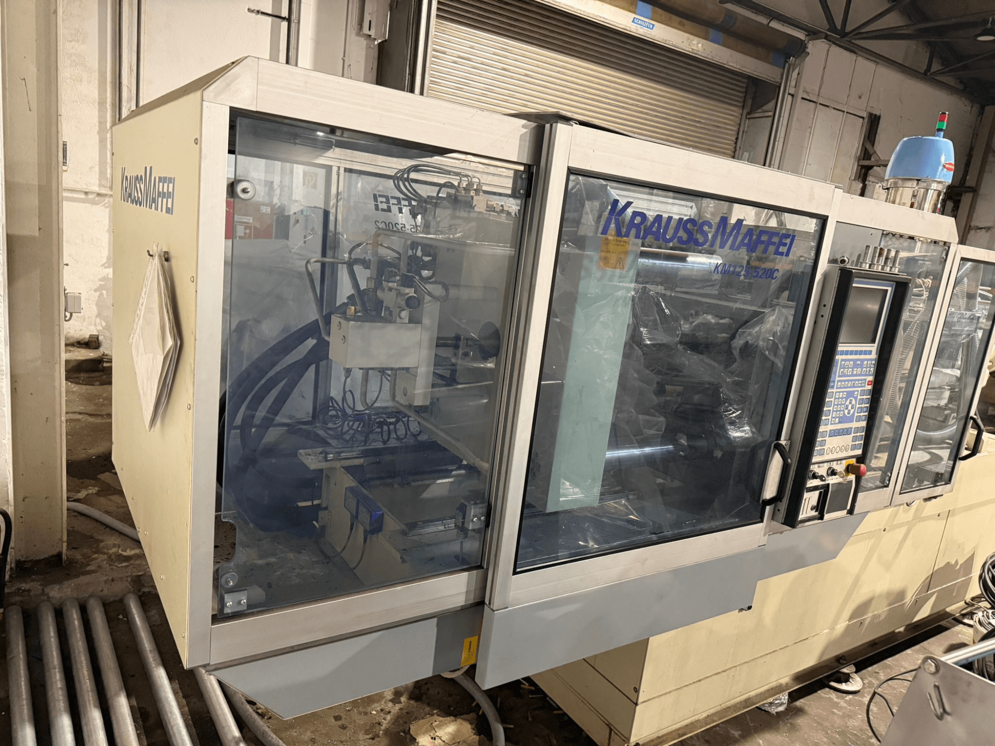 Krauss Maffei KM125-520C2 hydraulische spuitgietmachine, vooraanzicht met bedieningspaneel en transparante behuizing.