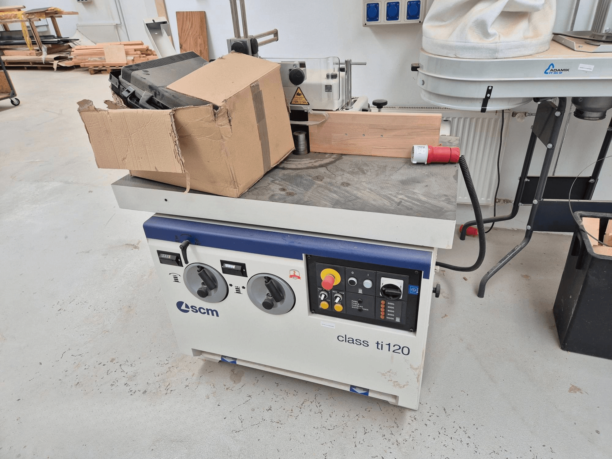 SCM klasse ti120 houtbewerkingsmachine, vooraanzicht, heeft een bedieningspaneel met knoppen en een kartonnen doos.