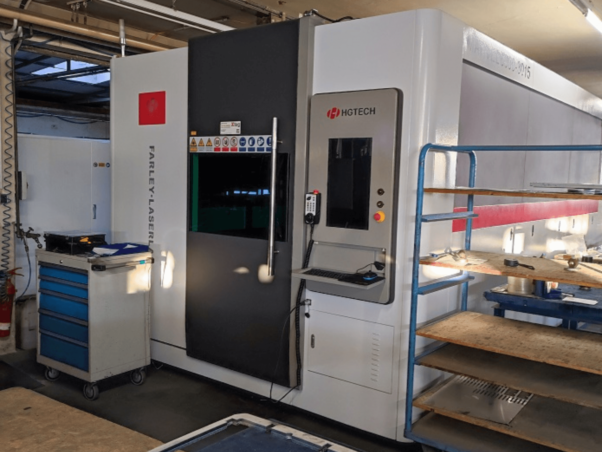 HGTECH Marvel 6000-3015 fiberlasersnijmachine, vooraanzicht met bedieningspaneel en aangrenzende opslag.