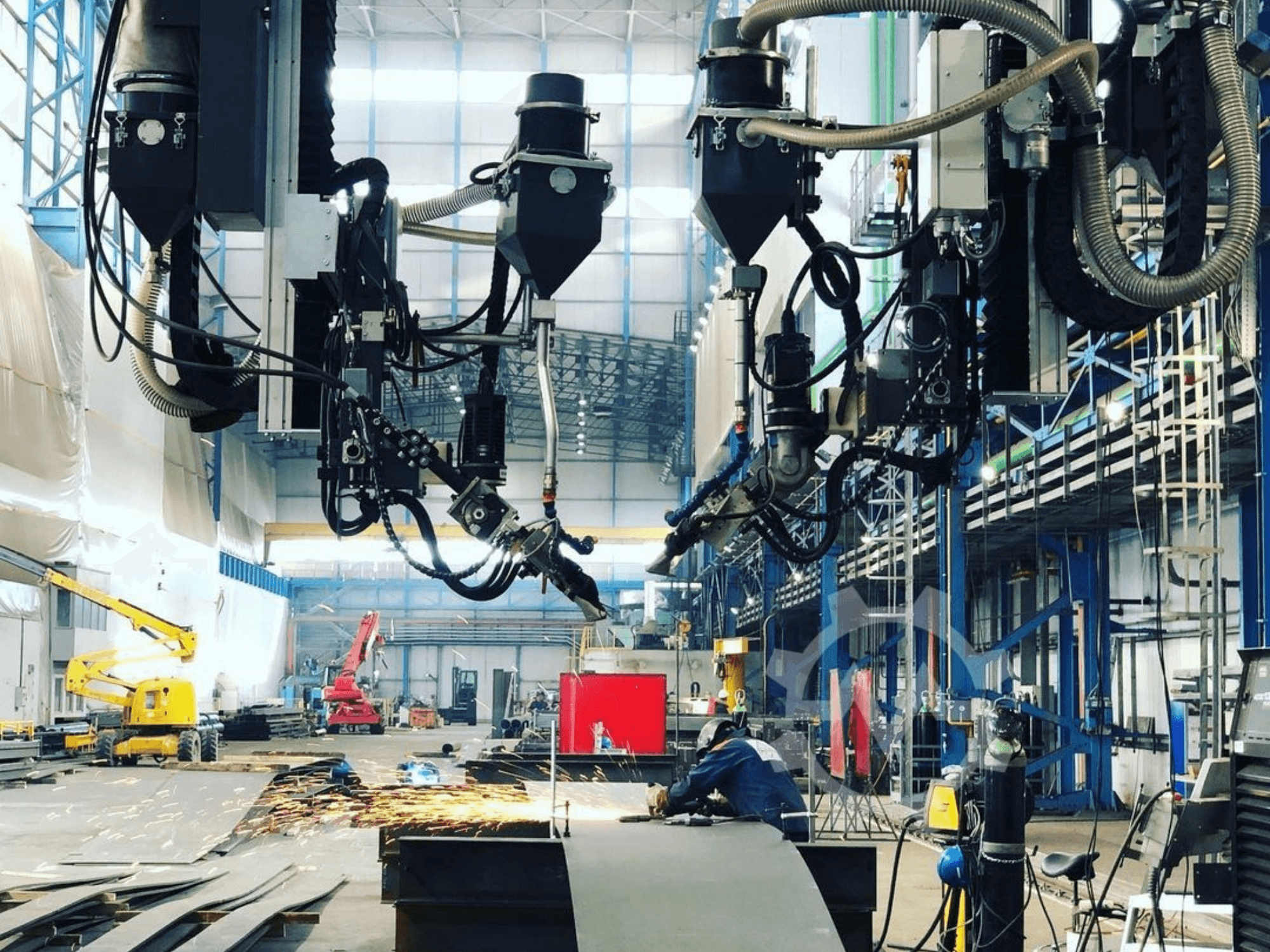 Robotische snijmachine in een industriële omgeving, met rondvliegende vonken, gezien vanaf de zijkant; voorzien van meerdere hulpstukken en slangen.