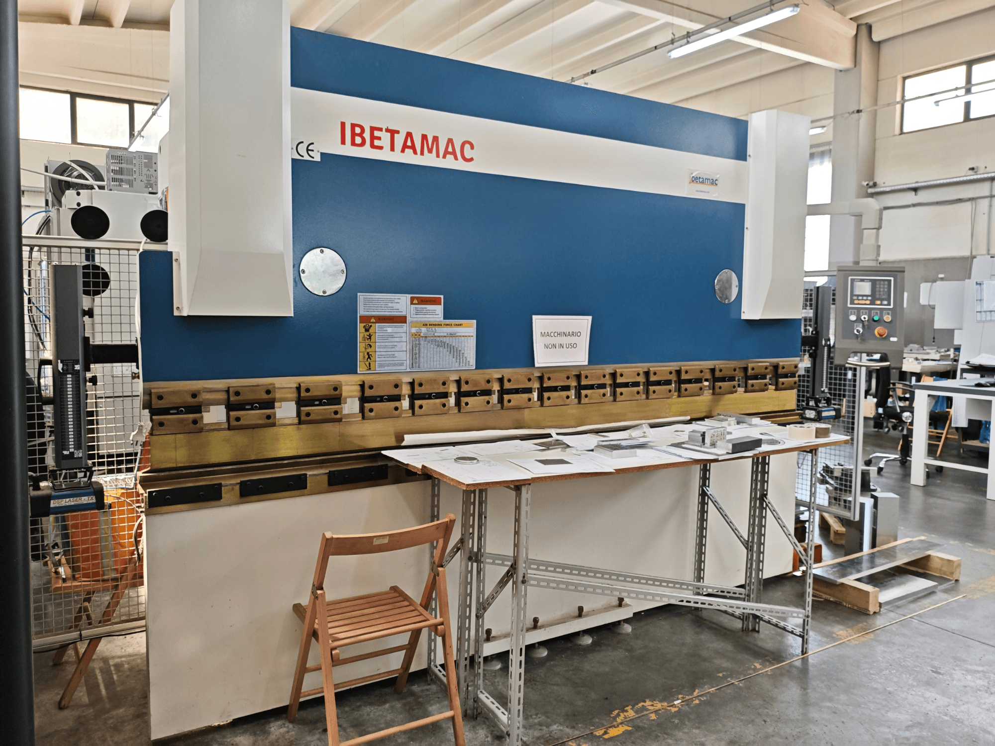 IBETAMAC 3200 100T kantpers in een werkplaats, zijaanzicht met bedieningspaneel, werkgebied en veiligheidsaanwijzingen.