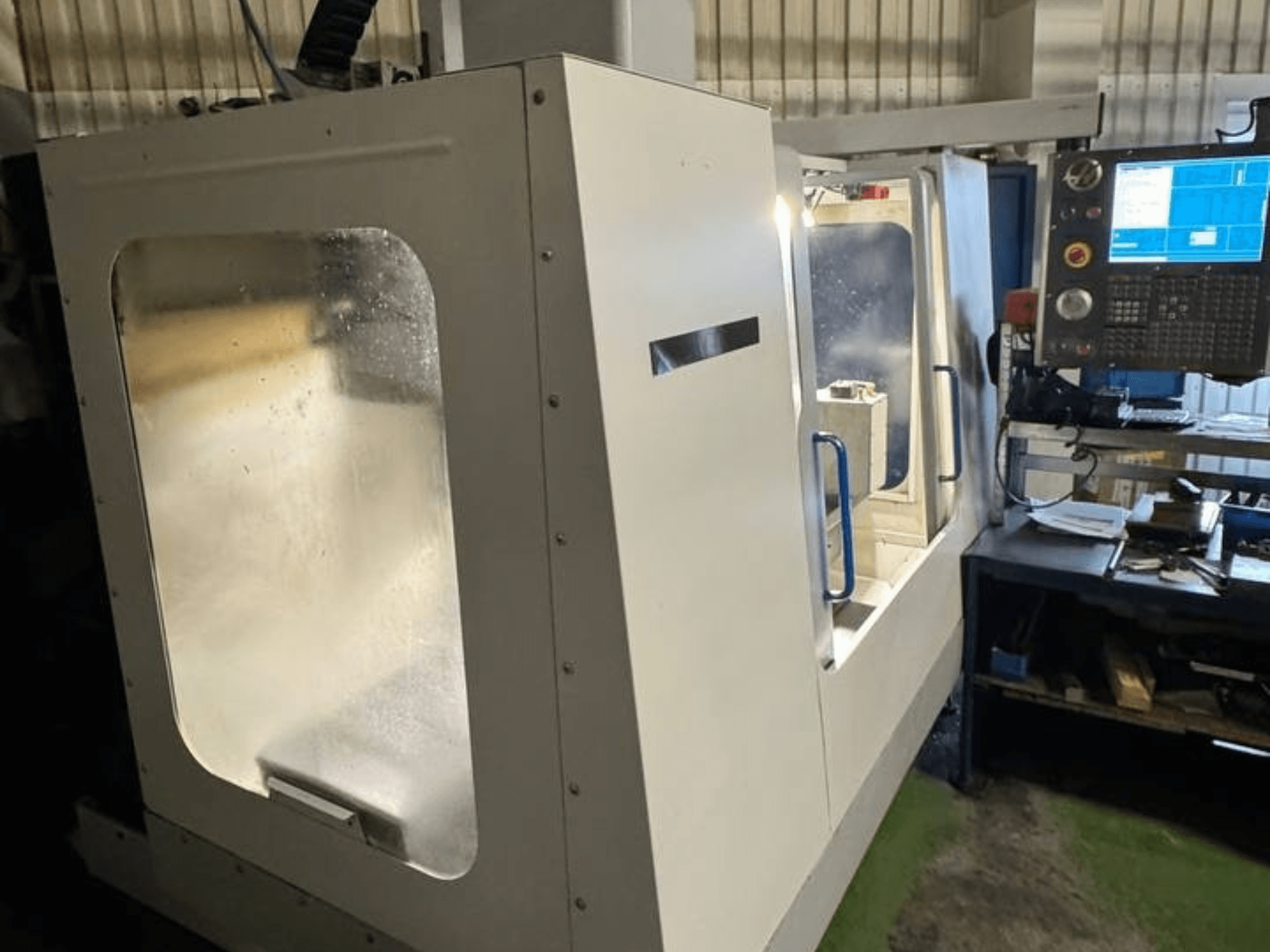 HAAS VCE 750 verticaal bewerkingscentrum in zijaanzicht, met bedieningspaneel en duidelijke veiligheidsbehuizing.