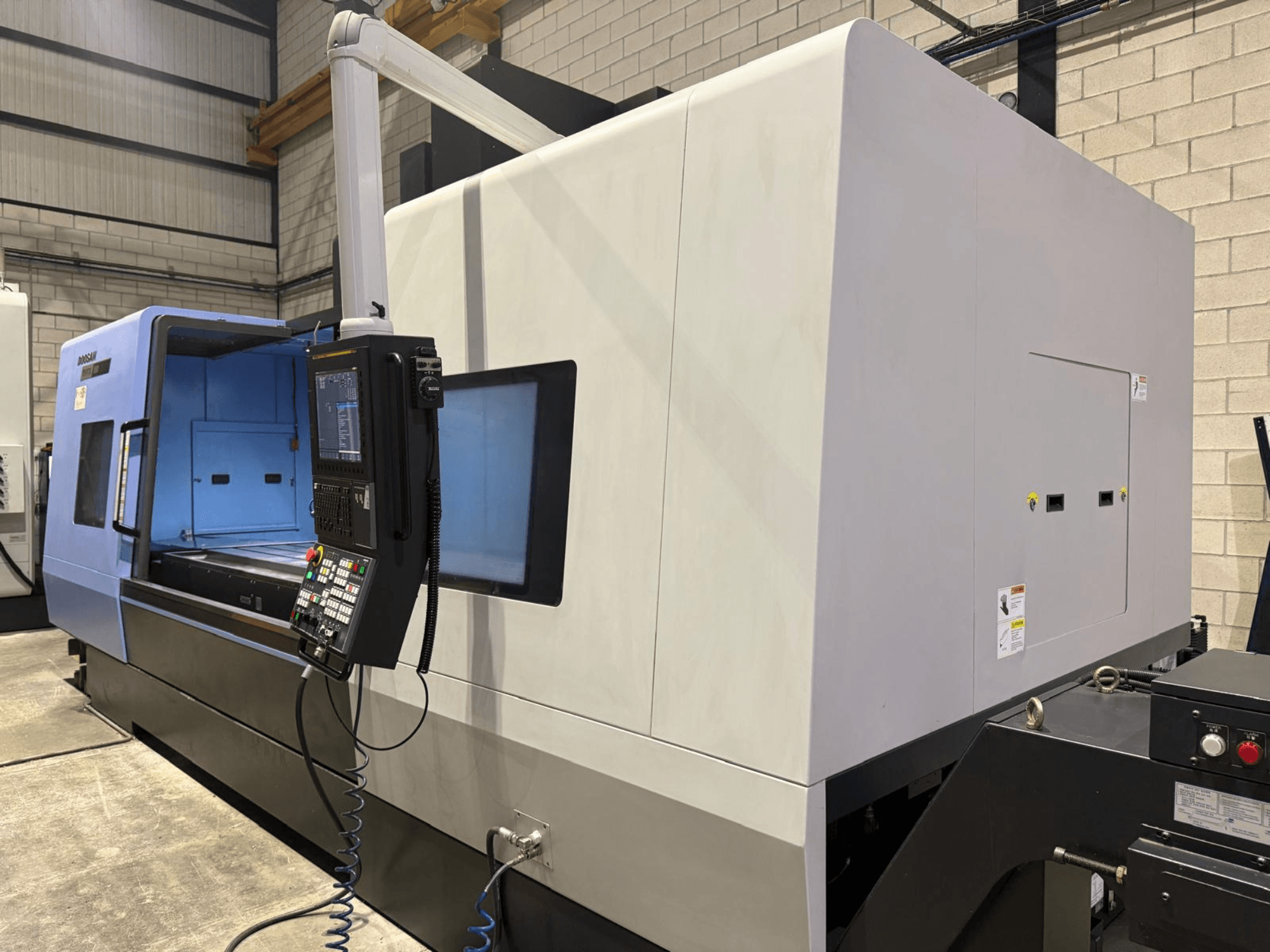 Industriële CNC draaibank, blauw met grijze buitenkant, vooraanzicht; voorzien van bedieningspaneel met knoppen en display voor nauwkeurige bewerkingen.