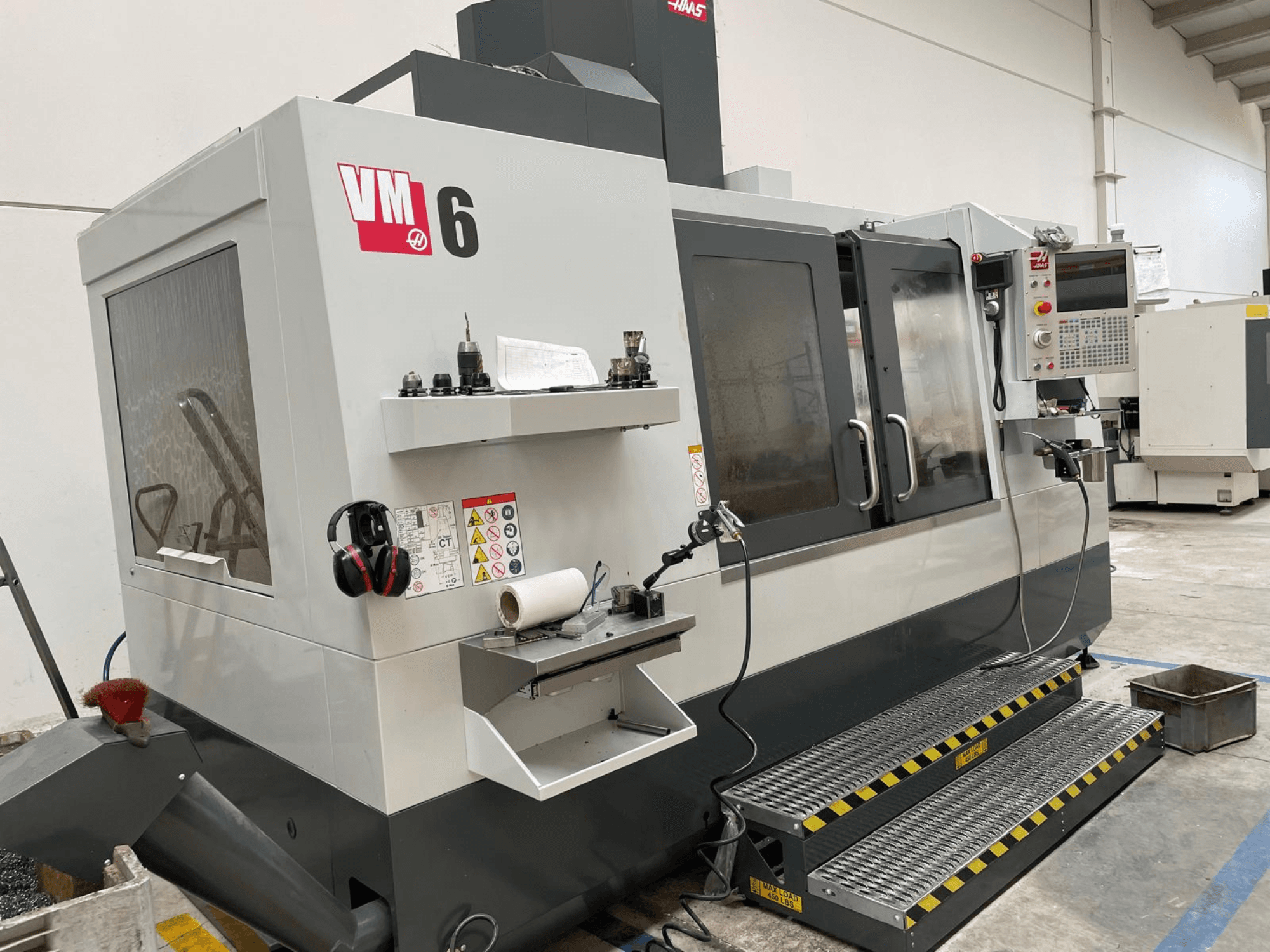 Haas VM-6 verticaal bewerkingscentrum, vooraanzicht met bedieningspaneel, gereedschaphouders en veiligheidsvoorzieningen.