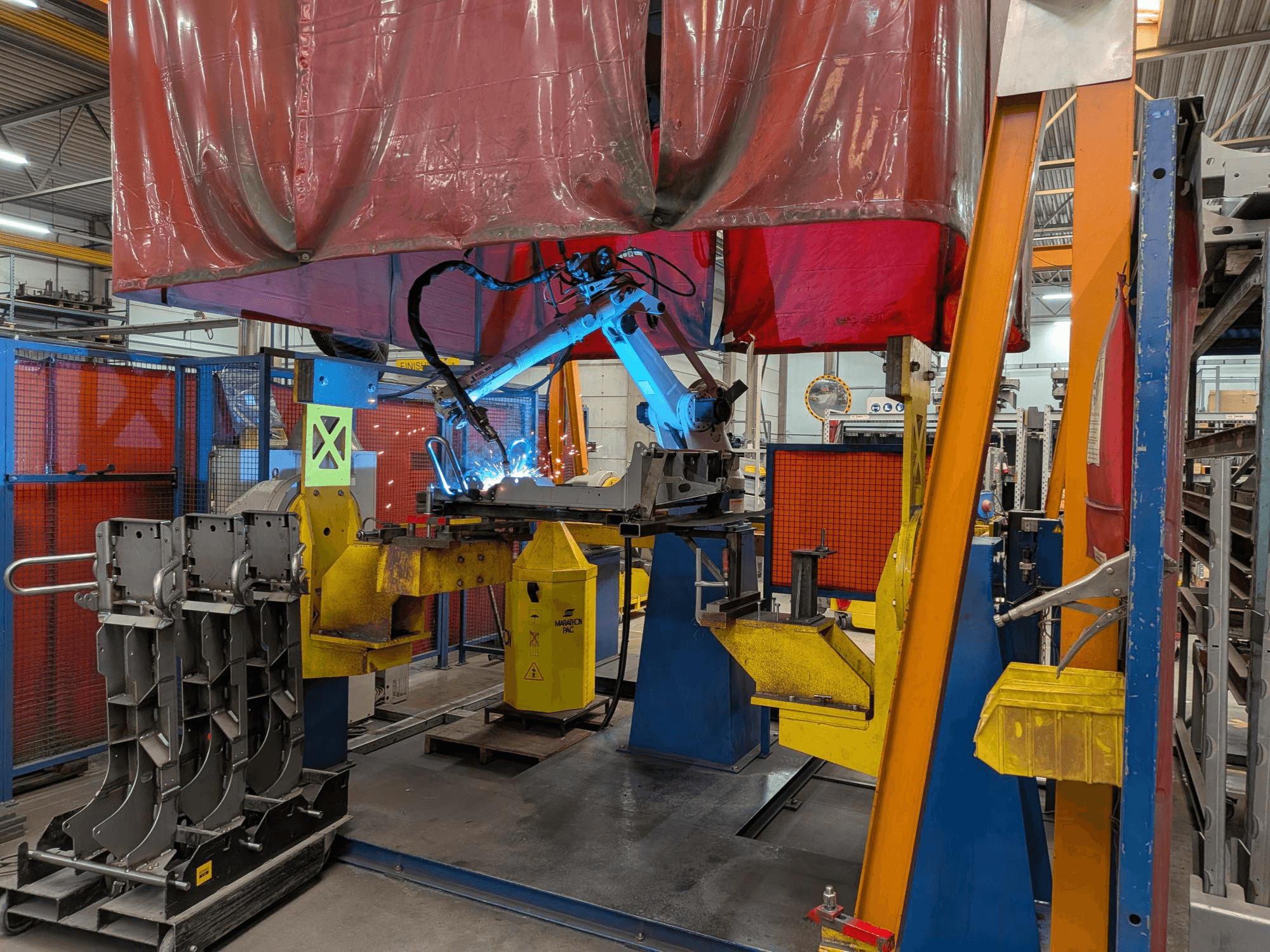 Lasrobot OTC Daihen DR4200 in actie, gezien vanaf de voorkant, met een felblauwe lasboog en een beschermkap.