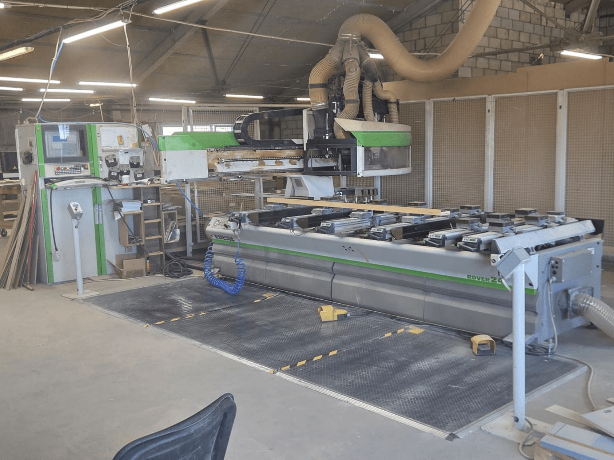 CNC-bewerkingscentrum BIESSE Rover 24S in een werkplaats, met een bedieningspaneel en een groot werkoppervlak met houten stukken.