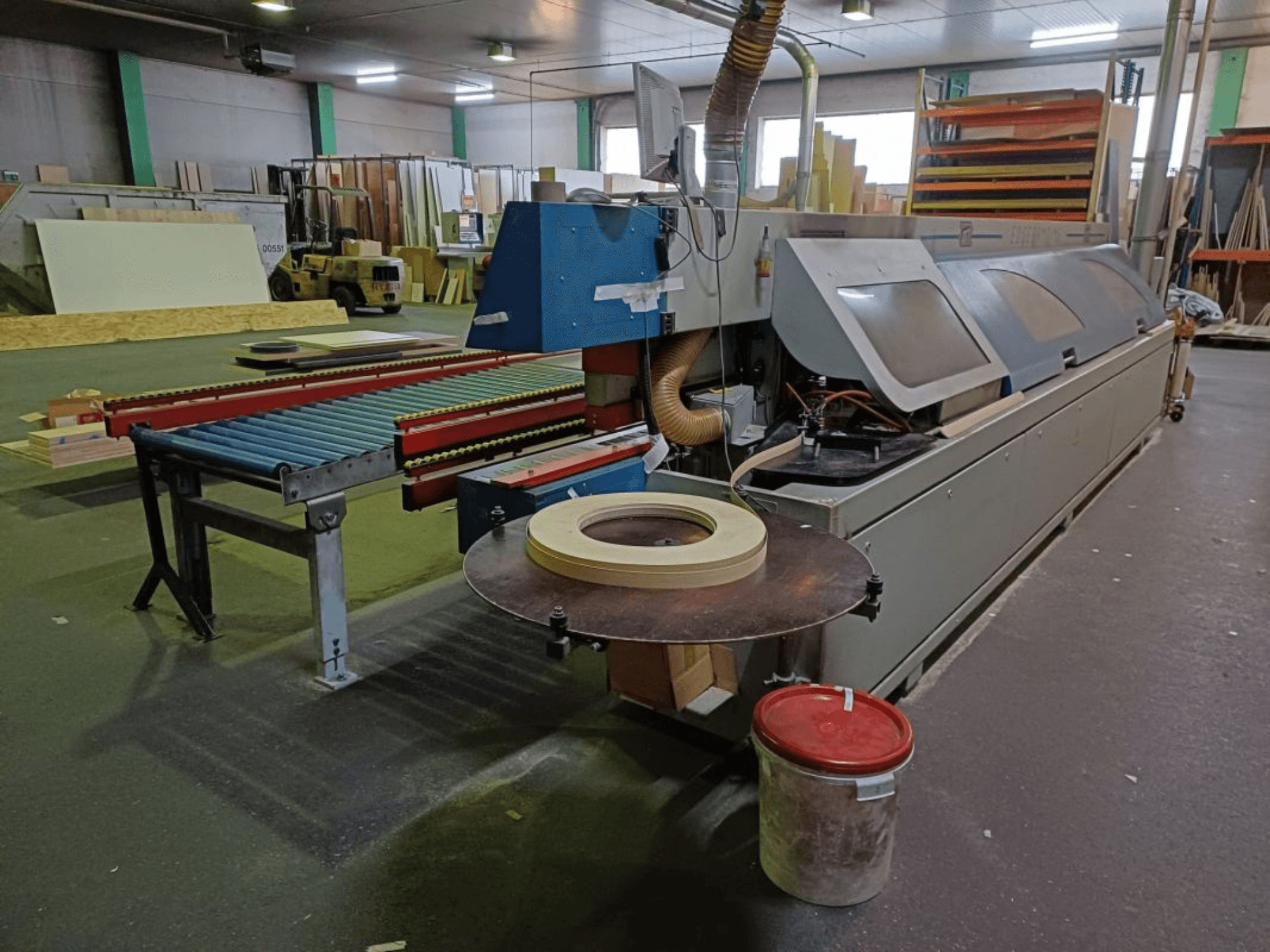 OTT TWISTER kantenaanlijper in een werkplaats, met een rollenbaan en cirkelzaag, gezien vanaf de zijkant.