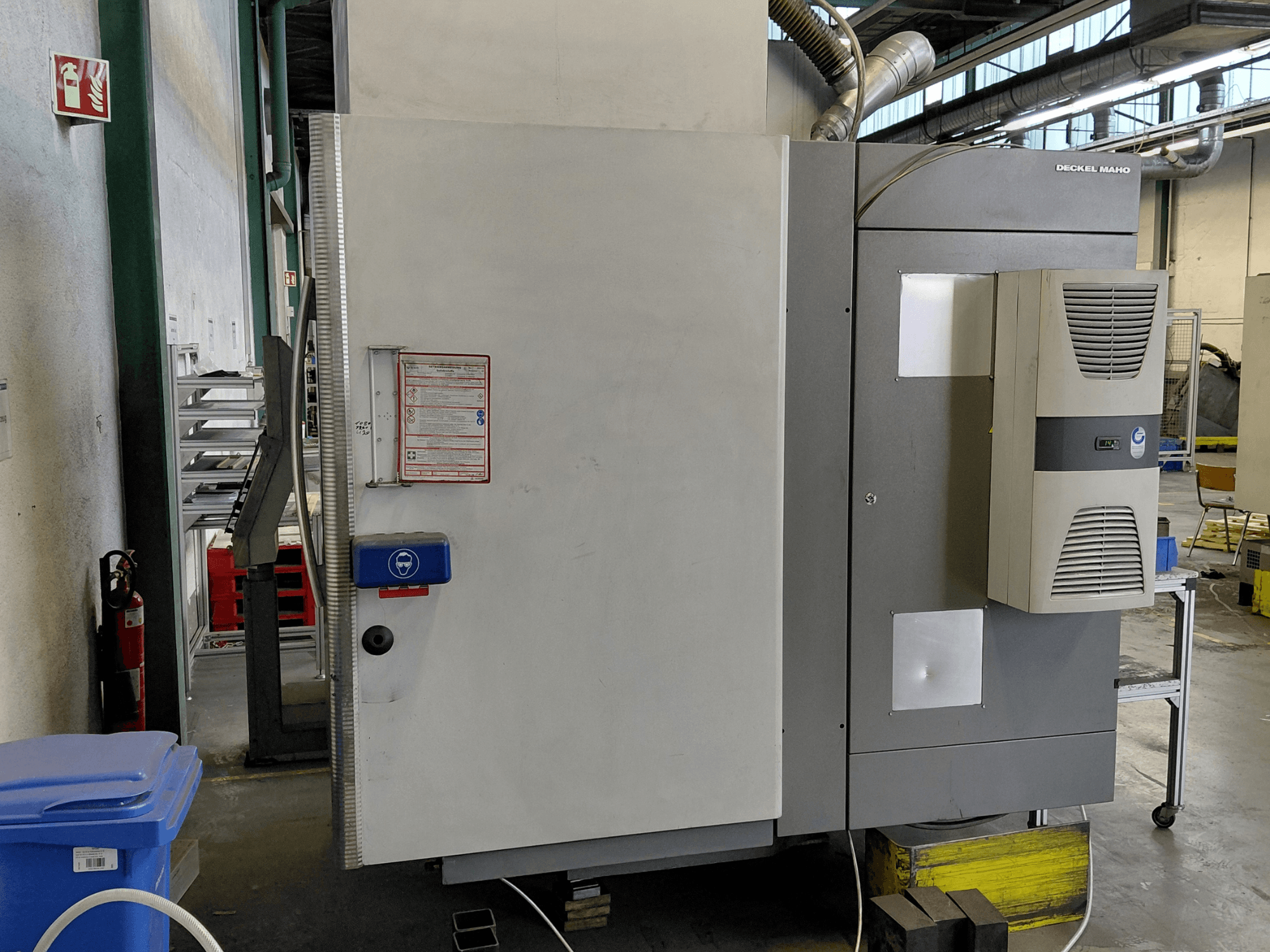 Zijaanzicht van DECKEL MAHO DMC 635 V verticaal bewerkingscentrum met bedieningspaneel en veiligheidslabels zichtbaar.