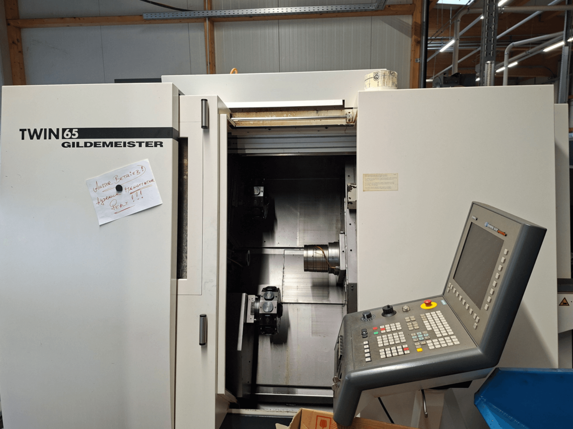 Gildemeister TWIN 65 CNC draaibank, vooraanzicht met bedieningspaneel en gedeeltelijk geopende kamer met zichtbare machines.