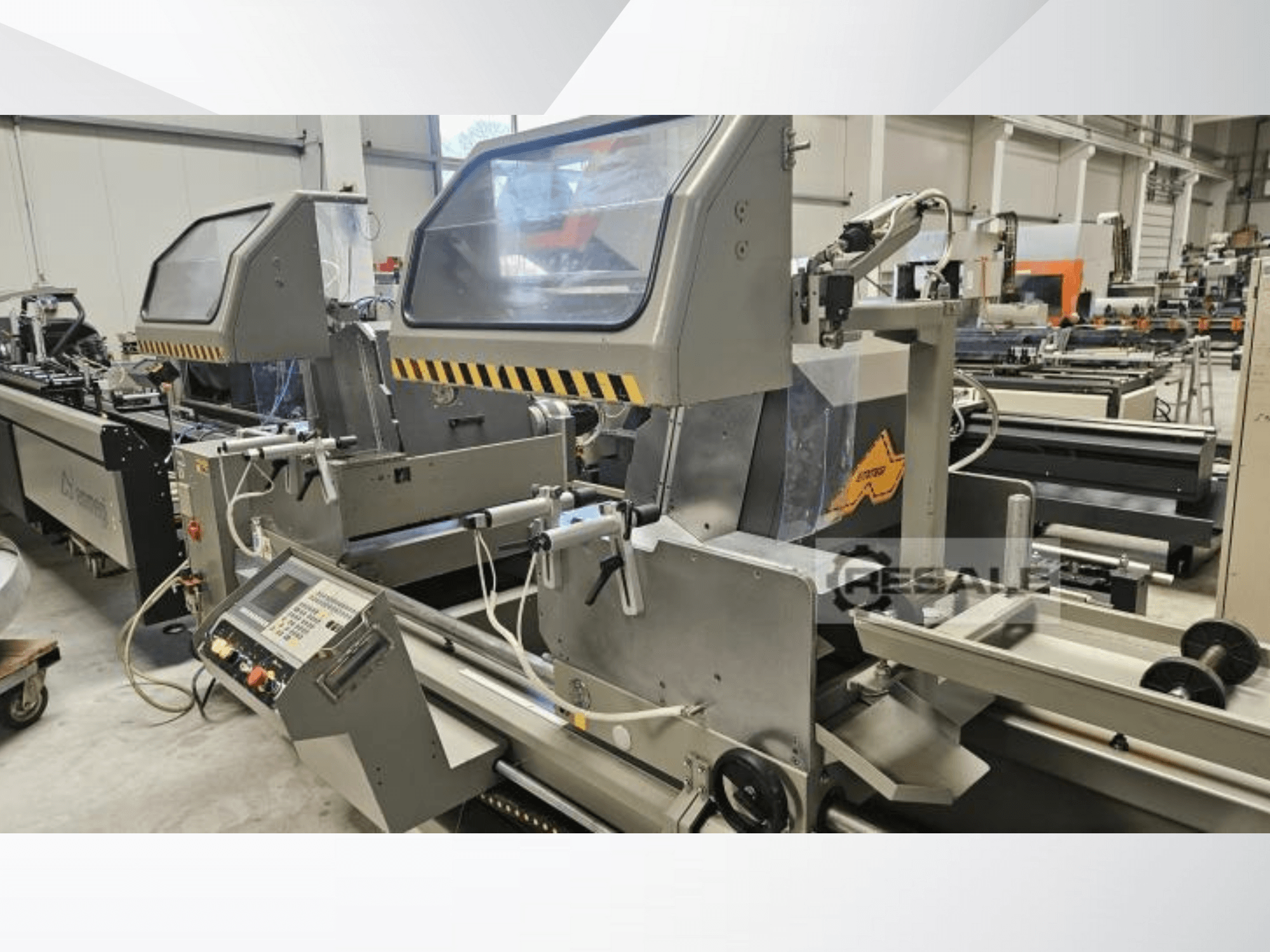 Dubbele zaagmachines in een fabrieksomgeving; vooraanzicht met bedieningspaneel, glazen afdekkingen en snijcomponenten.