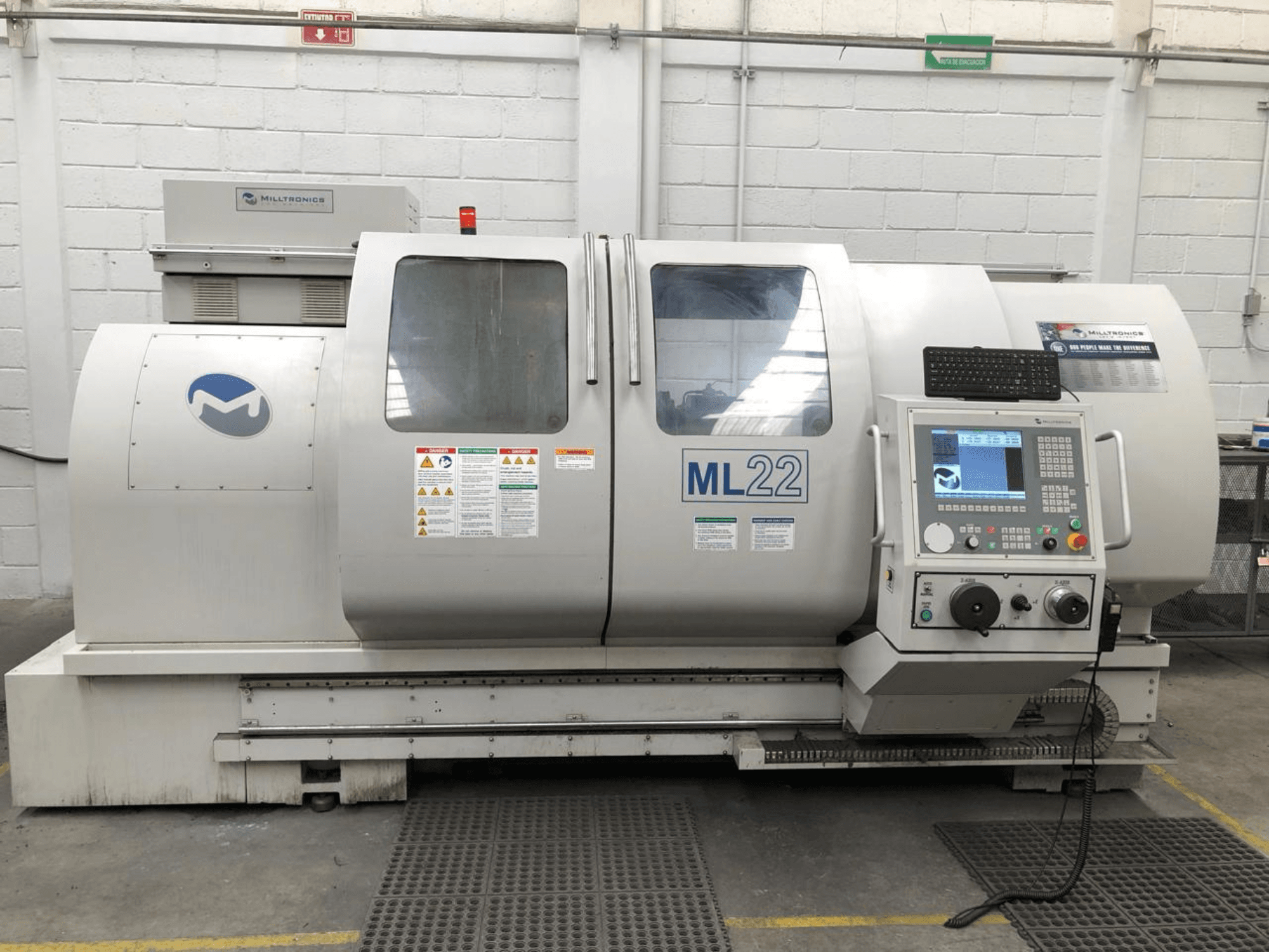 Verticaal bewerkingscentrum MILLTRONICS RH 20, vooraanzicht met bedieningspaneel, merklogo en veiligheidslabels op de machine.