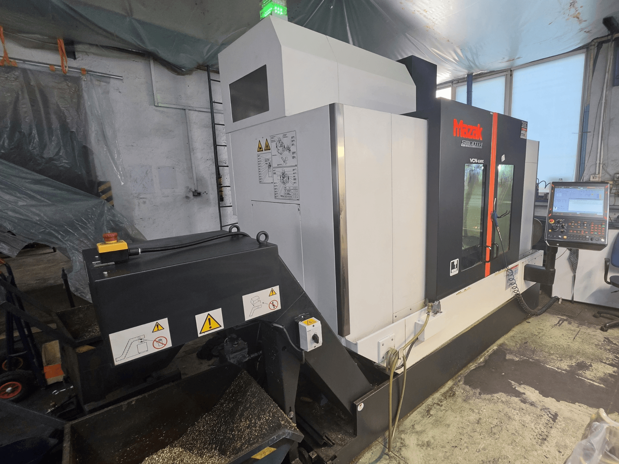 Verticaal bewerkingscentrum Mazak VCN-530C, vooraanzicht, met weergave van het bedieningspaneel, de gereedschapsketting en de bedrijfsindicatoren.