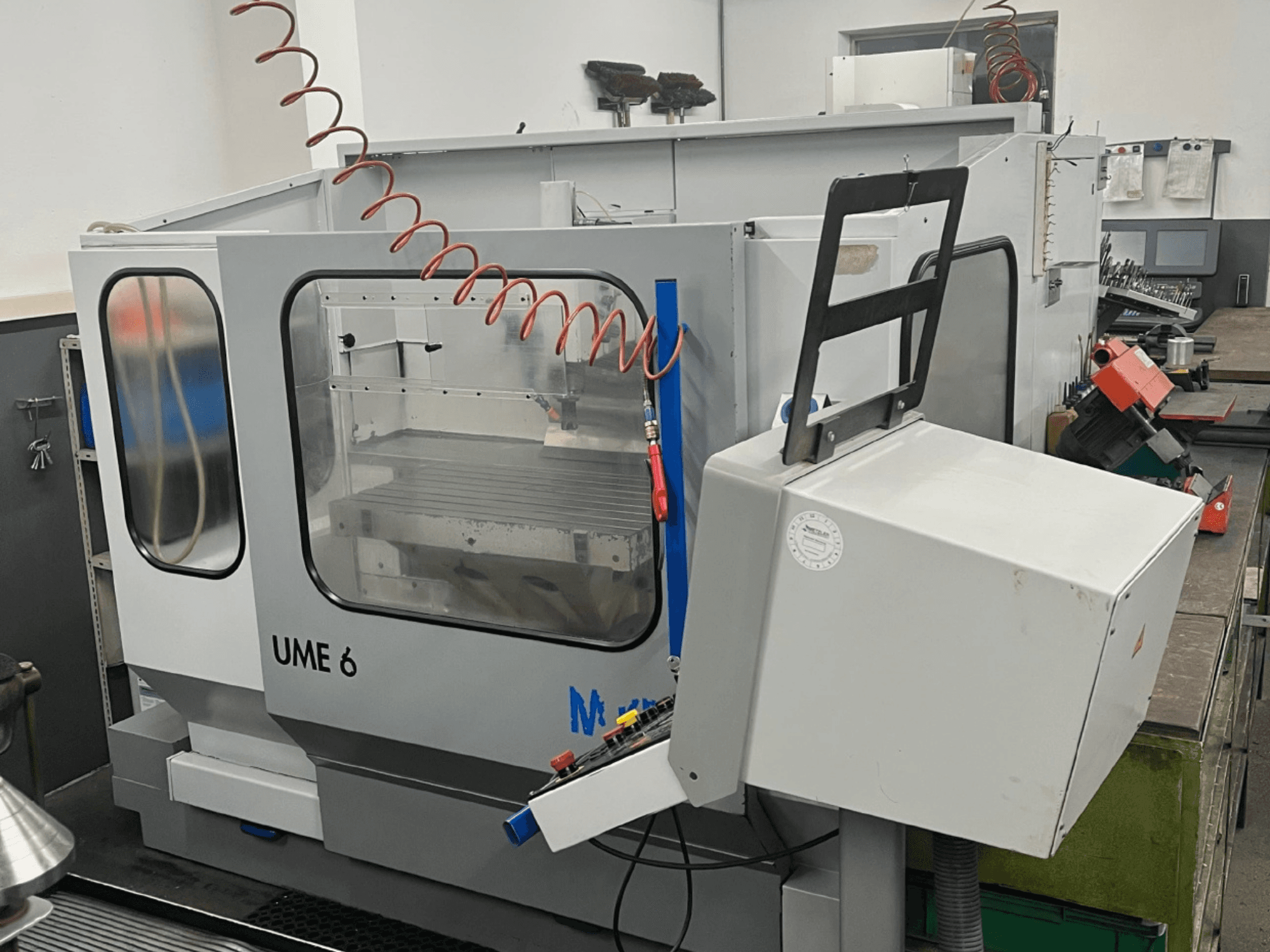MIKRON UME600 Universeel Bewerkingscentrum in een werkplaats, zijaanzicht met bedieningspaneel en beschermende behuizing.