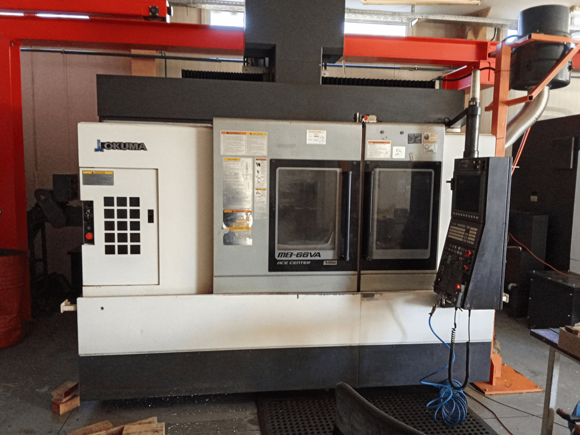 Okuma MB-66VA verticaal bewerkingscentrum, vooraanzicht met bedieningspaneel en dubbele kijkvensters voor toegang tot gereedschap.