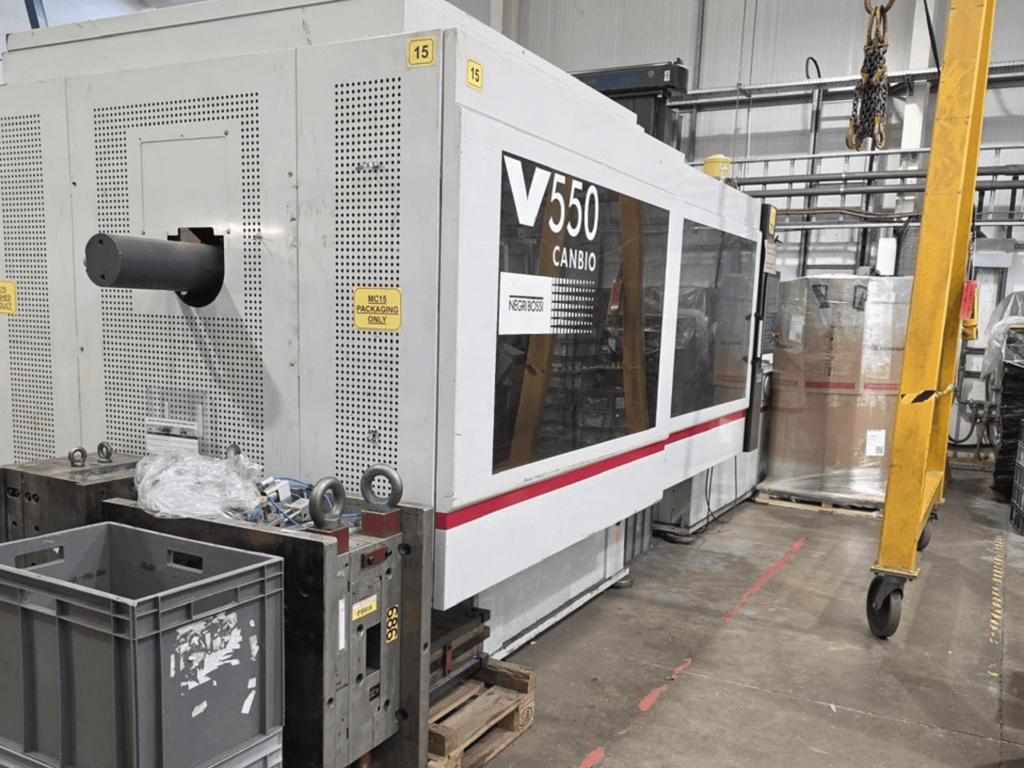 Negri Bossi V55000H-4250 hydraulische spuitgietmachine, zijaanzicht, met bedieningspaneel en grijze kratten op de voorgrond.
