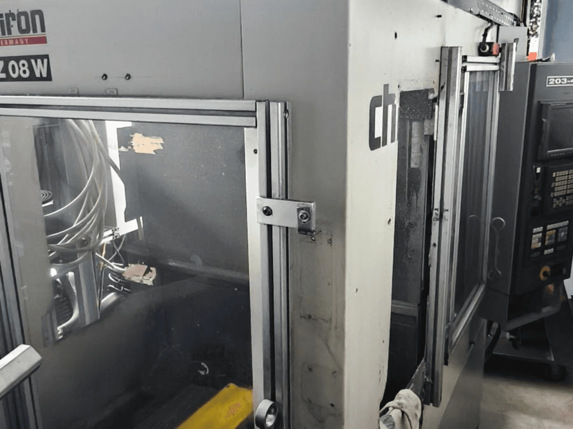 Verticaal bewerkingscentrum CHIRON FZ 08 W, vooraanzicht met bedieningspaneel en gedeeltelijk geopende deuren, met zichtbare interne componenten.