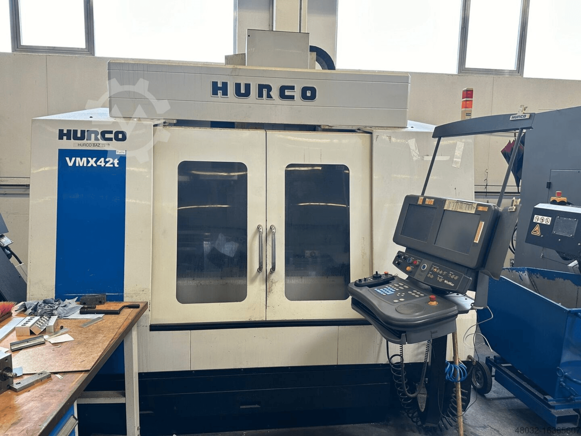 Hurco VMX42t verticaal bewerkingscentrum, vooraanzicht, met weergave van het bedieningspaneel en het zichtbare interieur met gereedschappen en werkstukken.