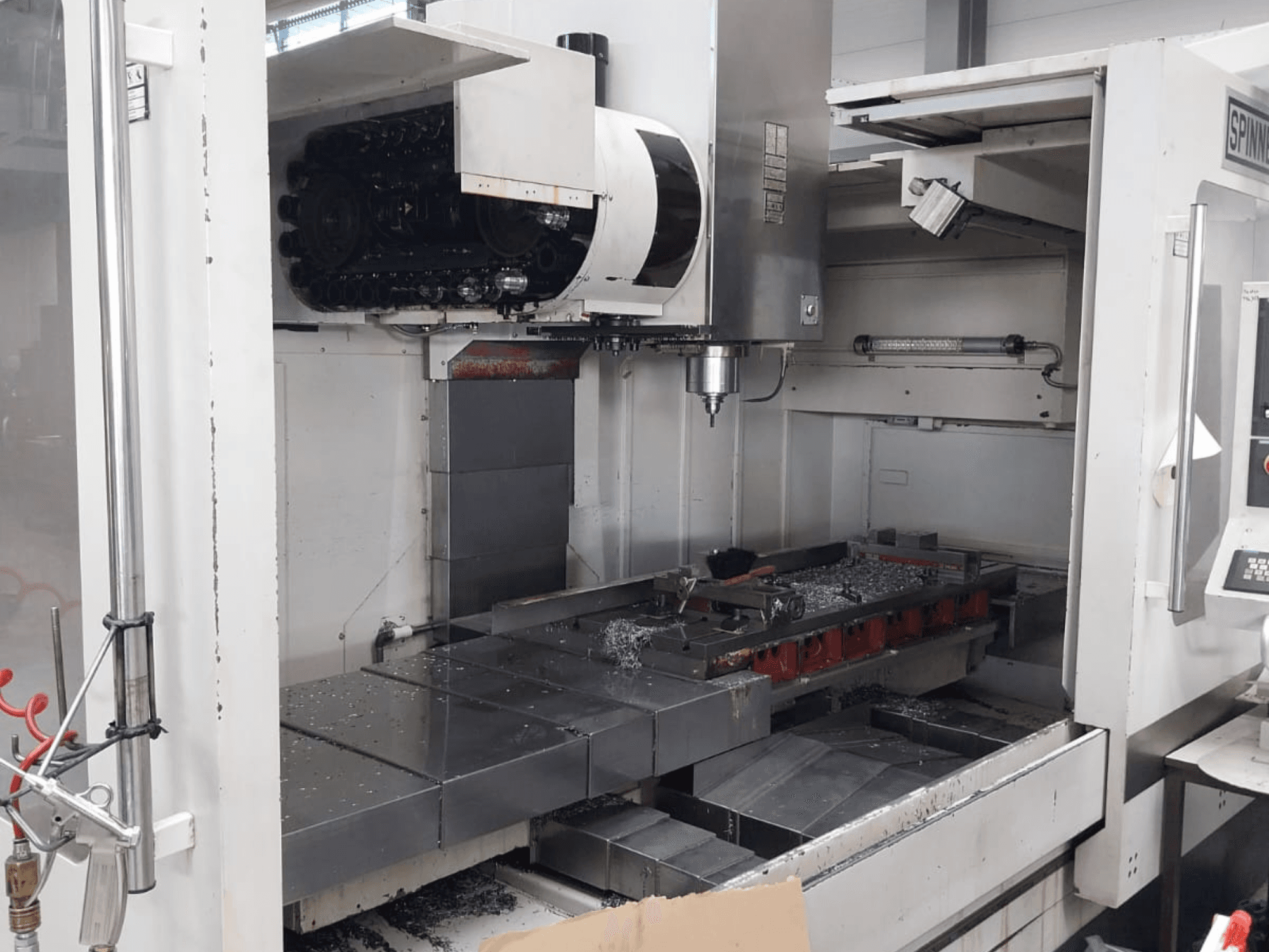 Vooraanzicht van het SPINNER MVC 1600 verticale bewerkingscentrum met de open werkruimte, de spindel en de metaalspanen op de tafel.