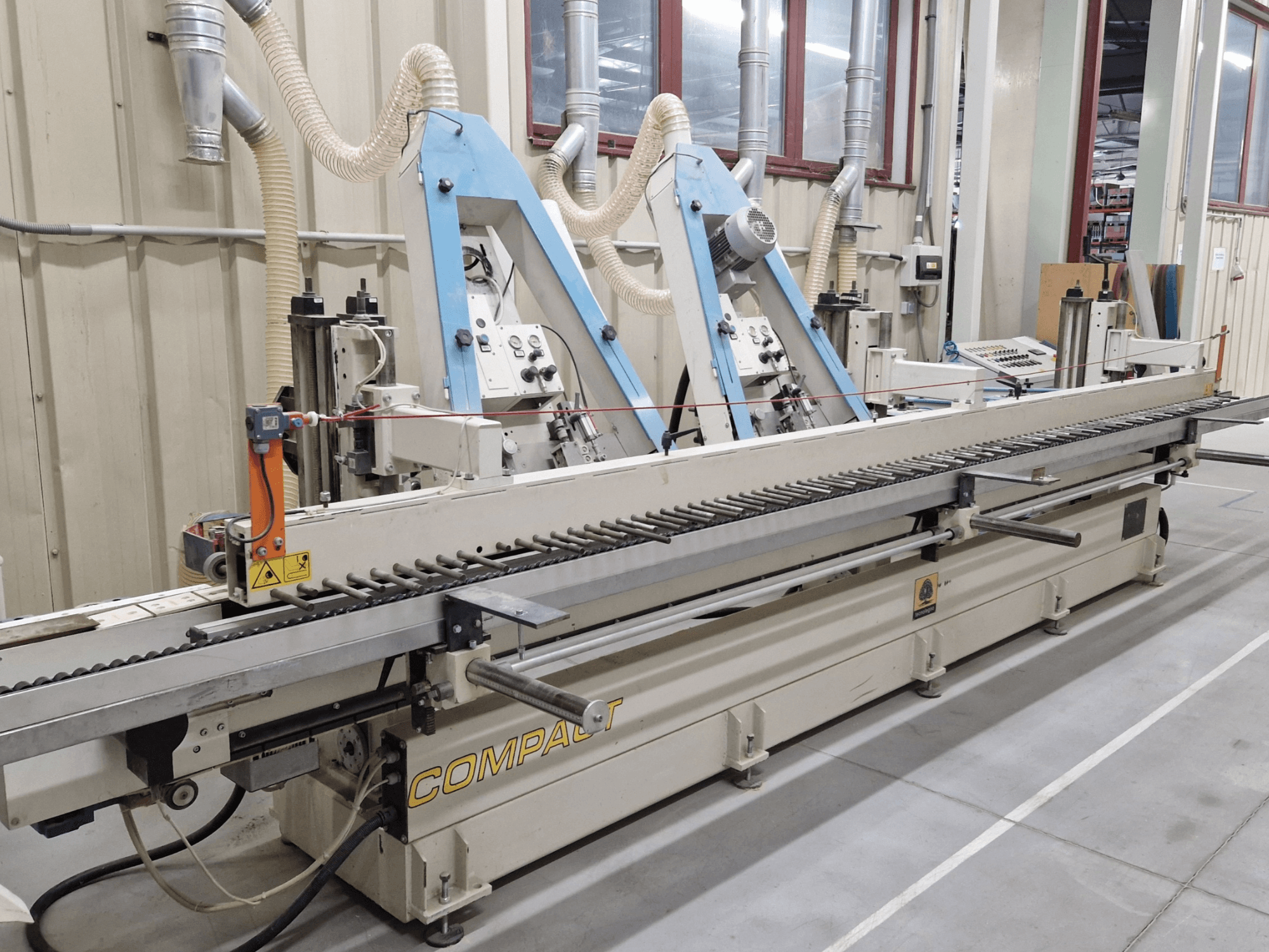 Bandschuurmachine TECNOLEGNO COMPACT 52 in een werkplaats, met het bedieningspaneel en het schuurbandmechanisme in zijaanzicht.