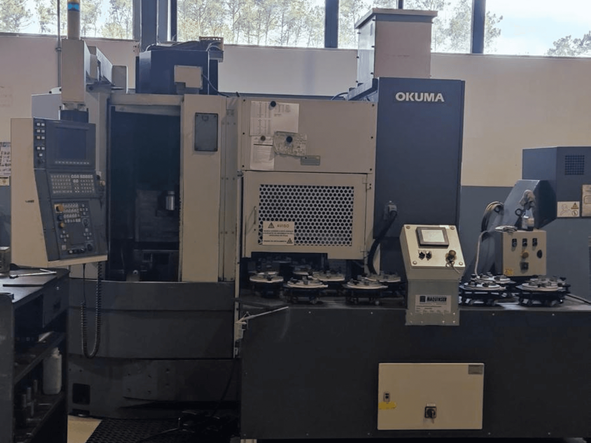 Okuma LVT300 verticale draaimachine in vooraanzicht, met bedieningspaneel, gereedschaphouders en bewerkingsgebied.