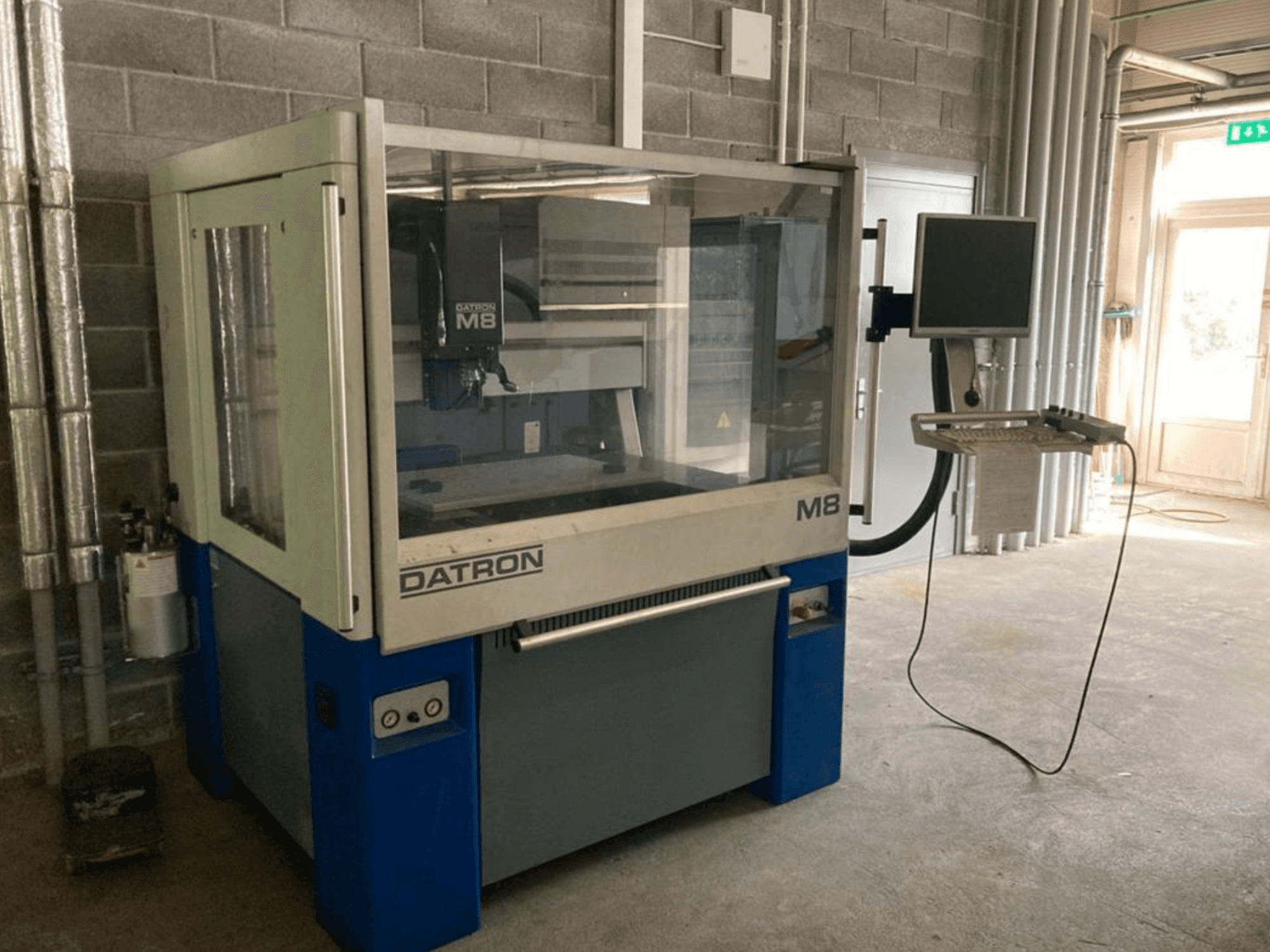Datron M8A verticaal bewerkingscentrum in een werkplaats, vooraanzicht met bedieningspaneel en touchscreen monitor.