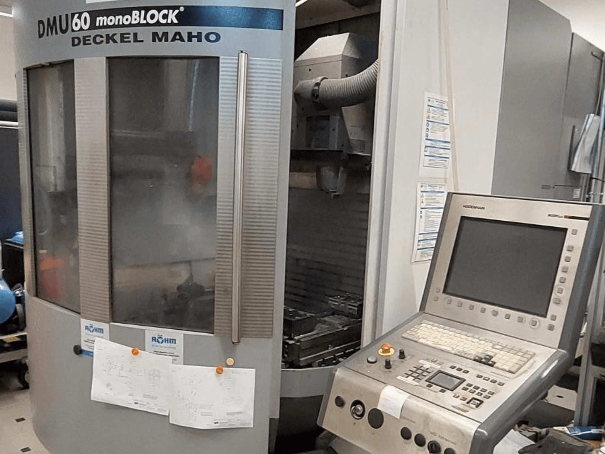 DMU 60 monoBLOCK van Deckel Maho, vooraanzicht van een CNC freesmachine met daaraan bevestigd een bedieningspaneel en technische tekeningen.