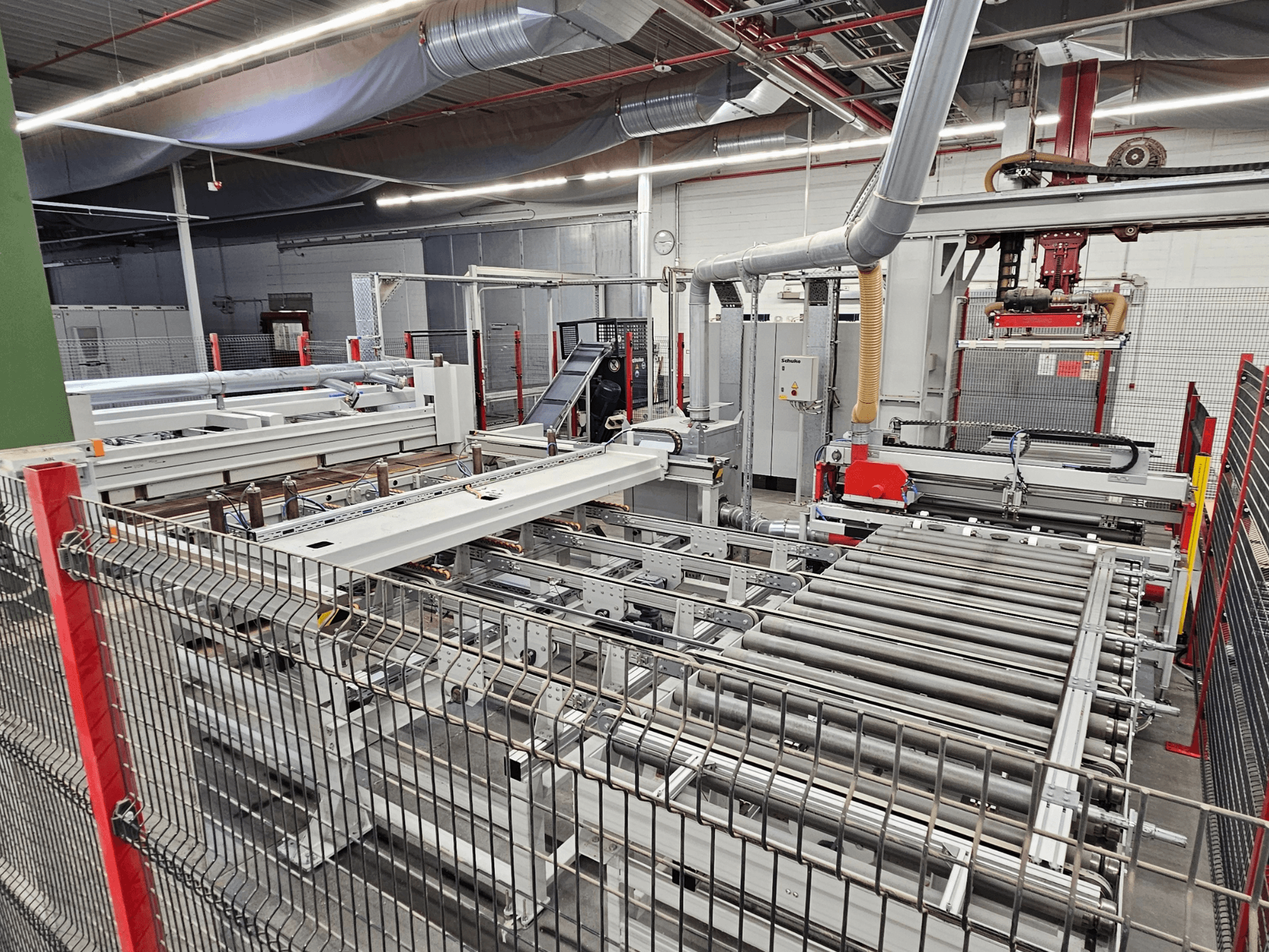 HOLZMA HPP81-3200 paneelzaag in vooraanzicht, met transportrollen en machineonderdelen in een werkplaats.